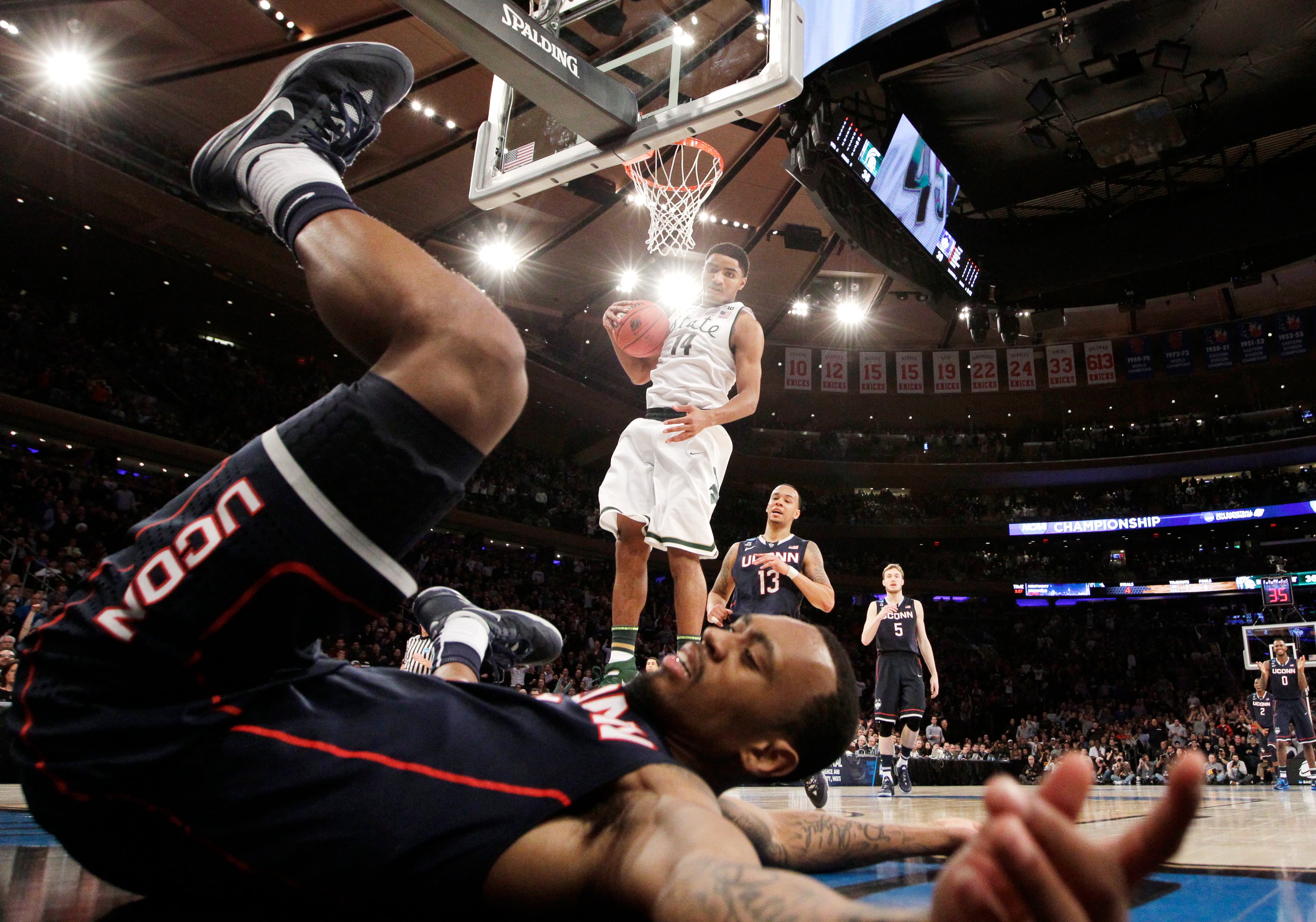 Connecticut's Ryan Boatright lands on the floor after scoring as Michigan State's Gary Harris holds the ball in the second half of a regional final at the NCAA college basketball tournament on Sunday, March 30, 2014, in New York. UConn won 60-54 to advance to the Final Four. (AP Photo/Frank Franklin II)