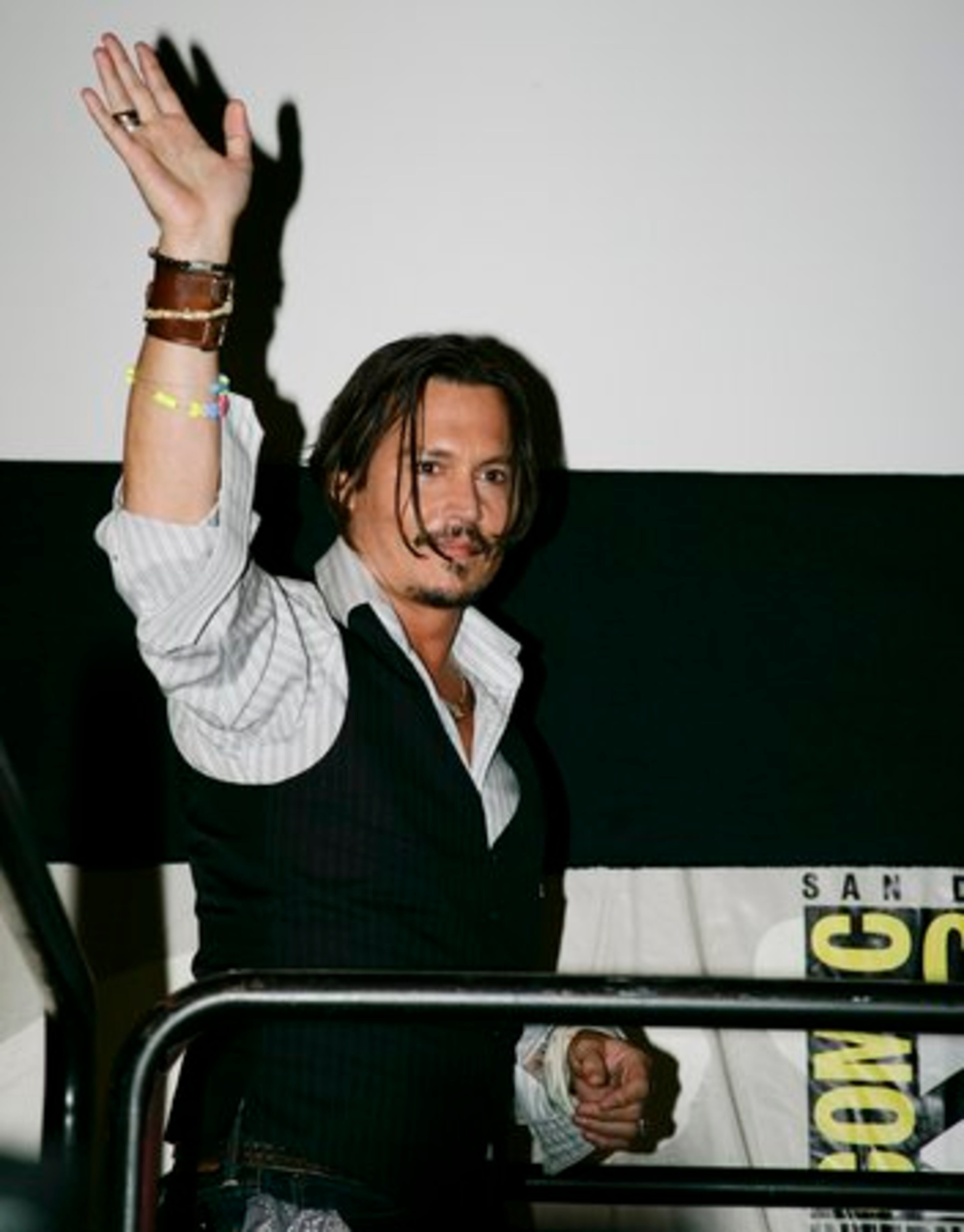 Actor Johnny Depp waves to fans as he makes an appearance at a panel held for his new movie "Alice in Wonderland."