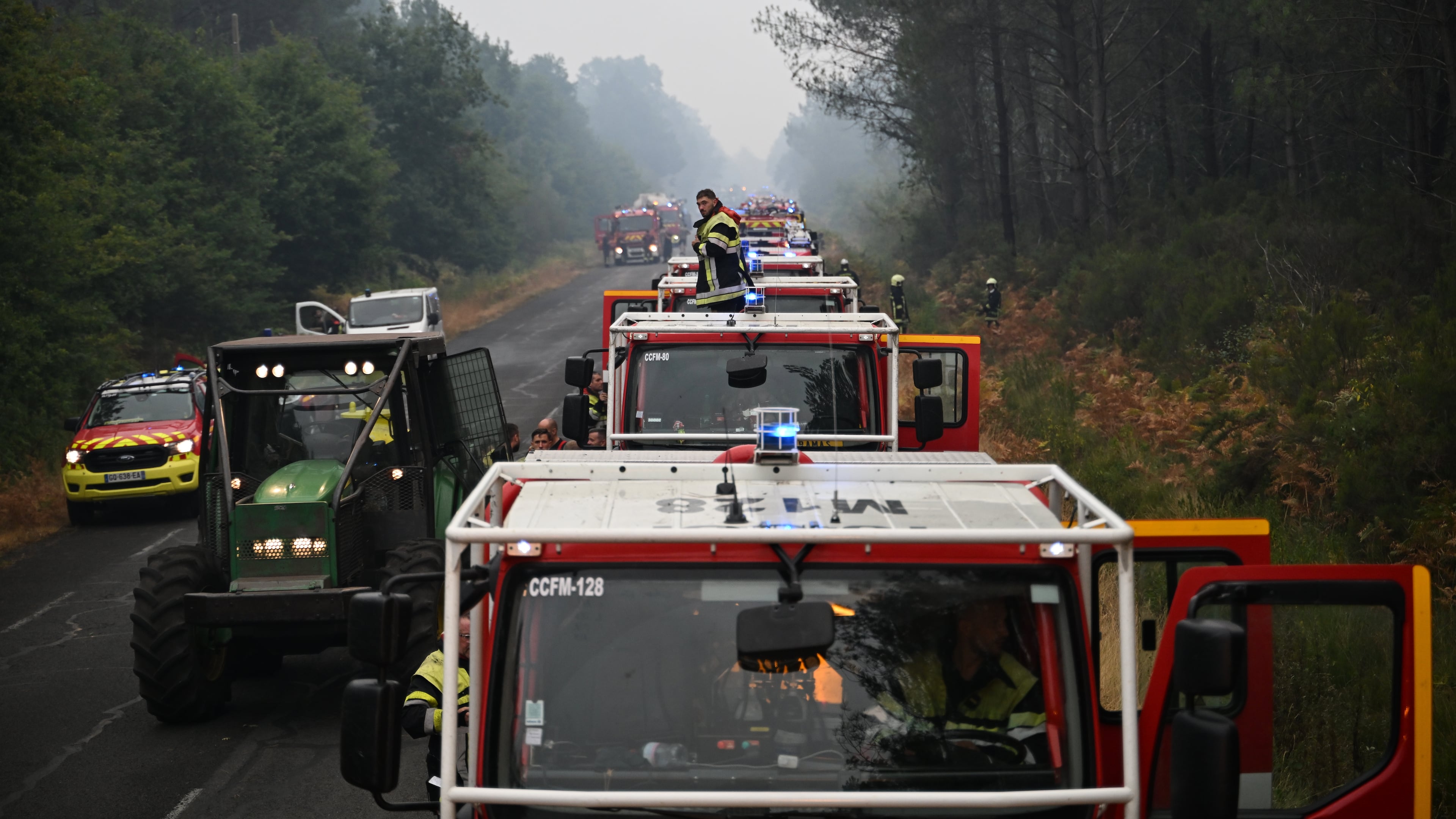 A firefighter stands on a truck on a road near Lacanau, southwestern France, Saturday, July 25, 2026, as wildfires rage in the area. (AP Photo/Emma Da Silva)