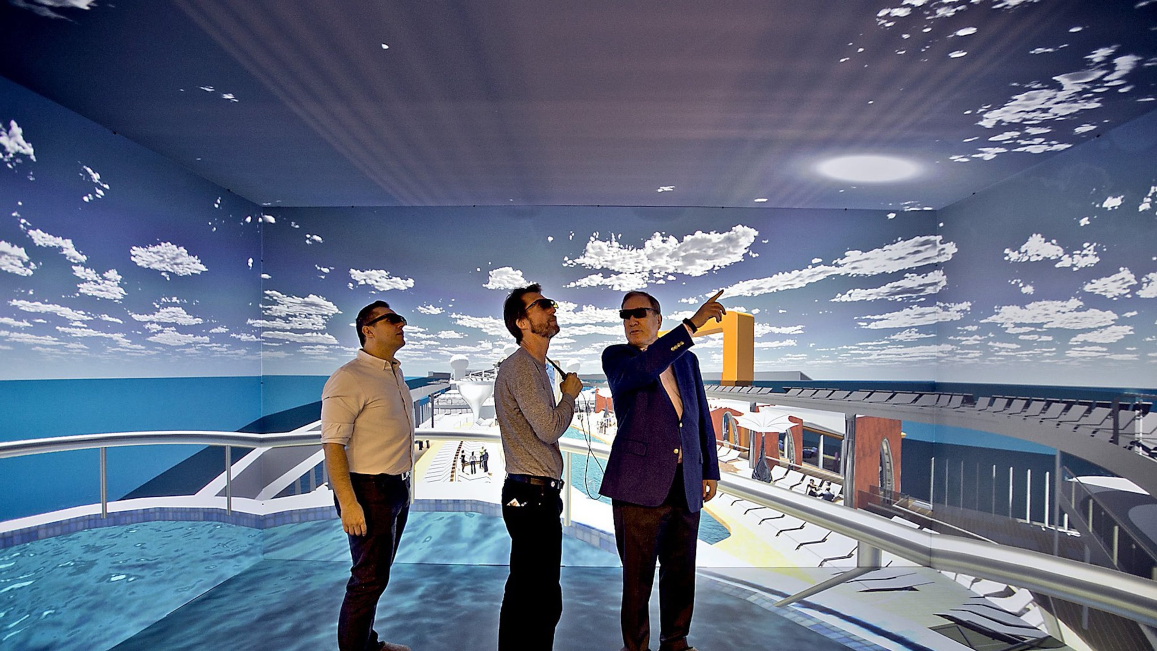 Wearing 3D glasses, Richard Fain, Chairman and CEO of Royal Caribbean Cruises Limited, right, chats with architects Paul Moreira, left, and Tom Wright, of WKK Architects, inside the 3D cave which is part of the new ship technology Royal Caribbean. (Patrick Farrell/Miami Herald/TNS)