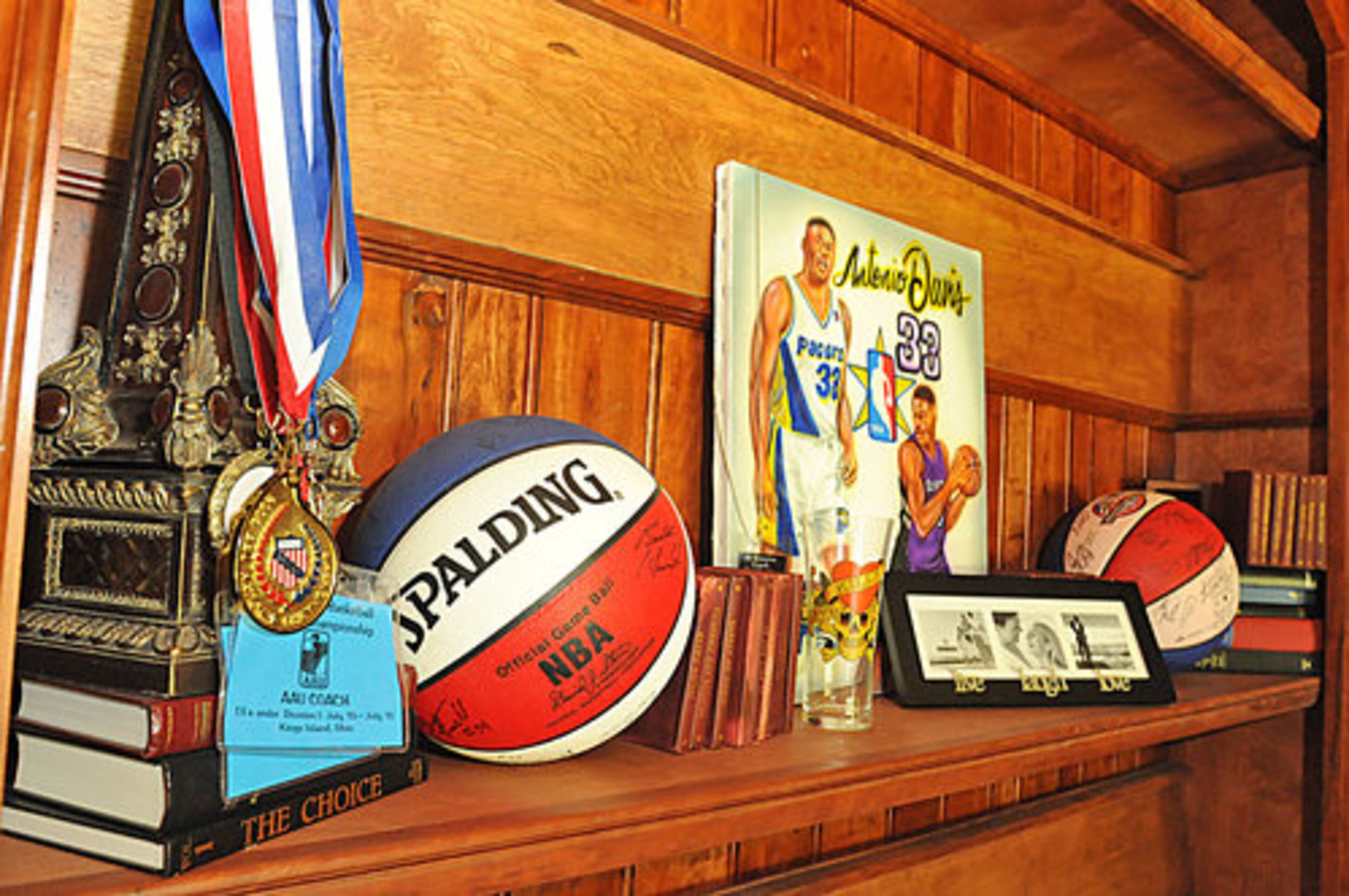 A closeup view of Antonio's collection of sports memorabilia, including signed basketballs and medallions recognizing his achievements as coach of the Georgia Ice. The team cinched their second-consecutive AAU (Amateur Athletic Union) girls basketball 13-and-under national championship.