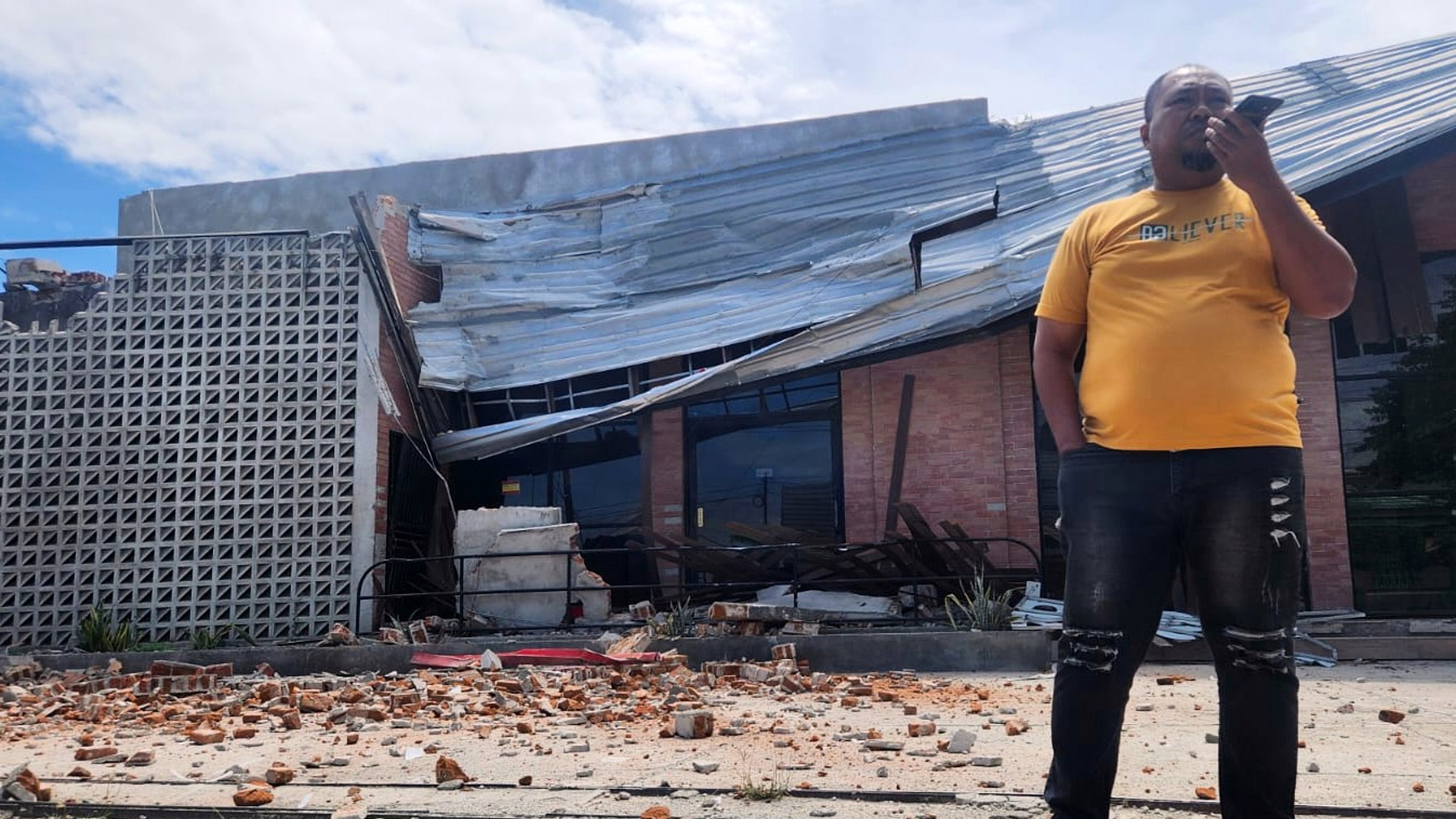A man talks on his mobile phone near a building damaged in an earthquake in Palu, Central Sulawesi, Tuesday, June 16, 2026. (AP Photo/Josua Marunduh)