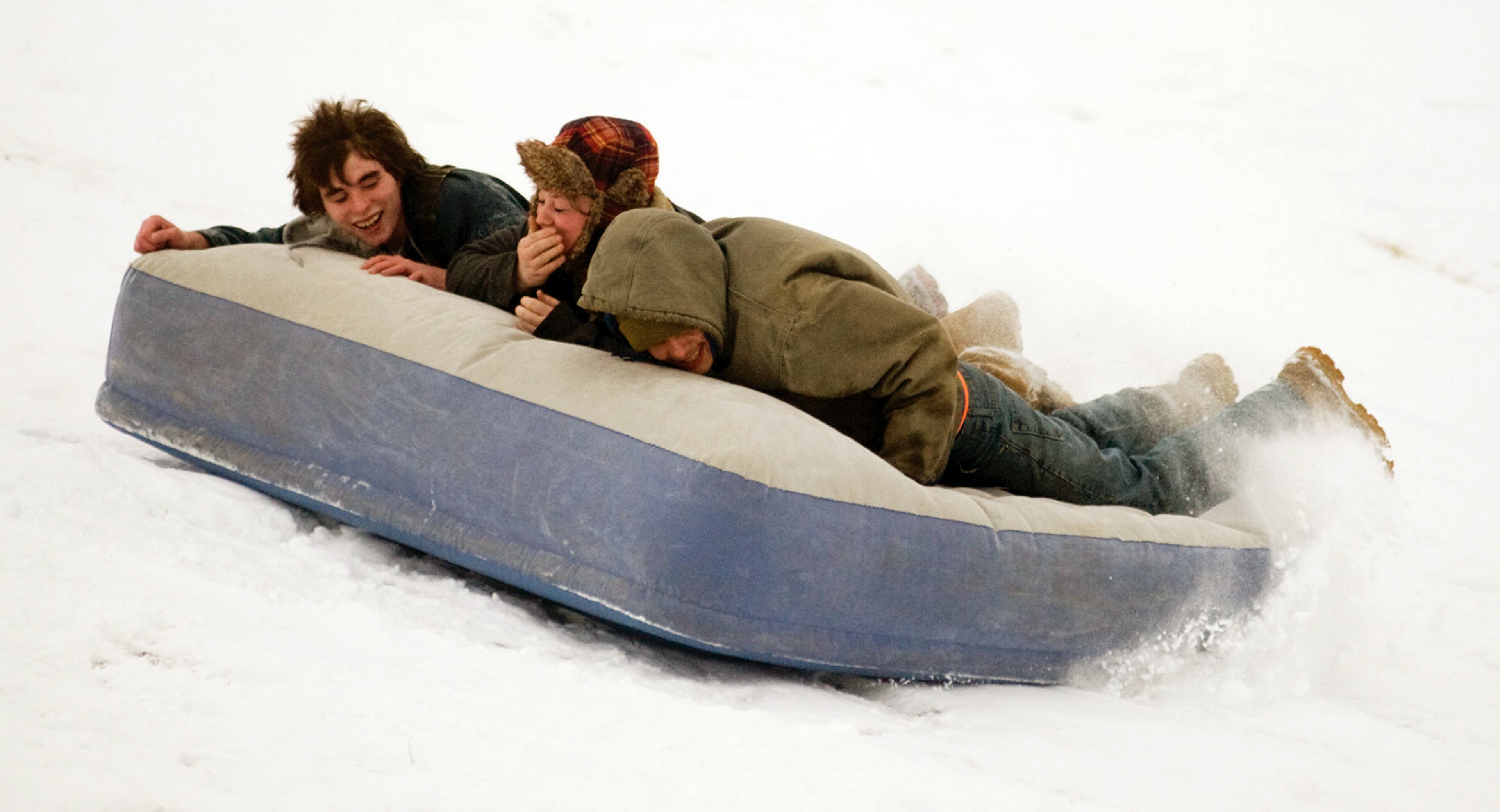 Michael Brown, 18, left, Robin Patch, 21, center, and Johnathon Best, 21, use an air mattress as a sled Sunday, March 2, 2014, at Hudson Family Park in Portland, Ind. Jay County was spared the bulk of the winter storm as it got 3 inches of snow this weekend while more severe weather hit northwest and southern Indiana. (AP Photo/The Commercial Review, Ray Cooney)