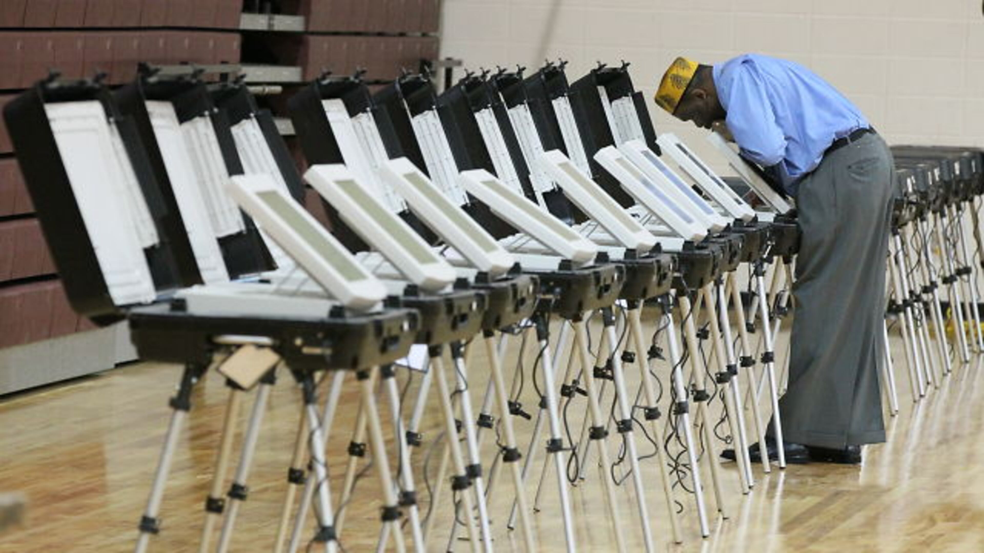 Poll manager Melvin Davis Jr. gets the voting machines ready at the Grady High School polling place early on Tuesday morning.