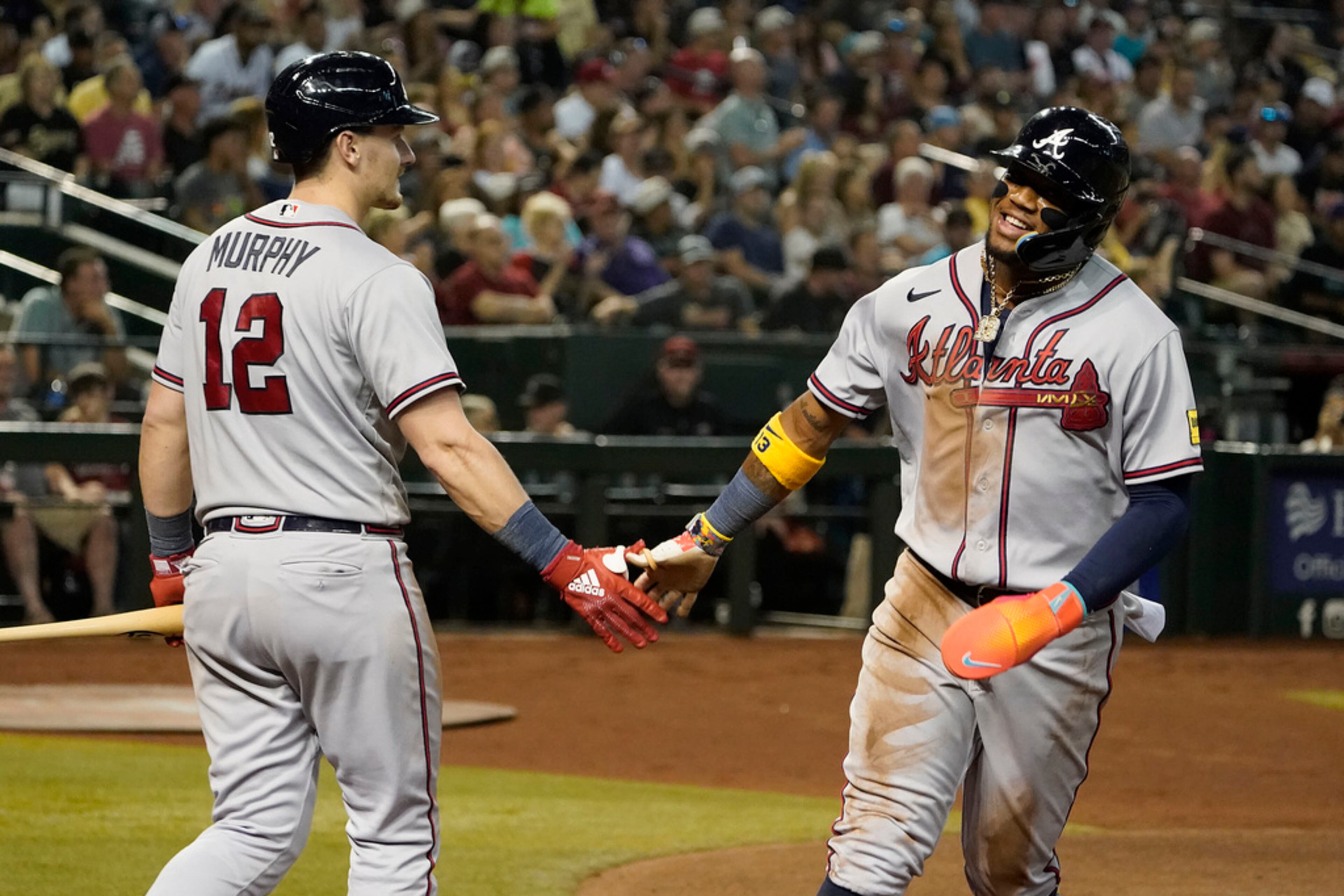 Atlanta Braves' Ronald Acuña Jr., right, gets congratulations from Sean Murphy after scoring against the Arizona Diamondbacks during the third inning of a baseball game Saturday, June 3, 2023, in Phoenix. The Braves won 5-2. (AP Photo/Darryl Webb)