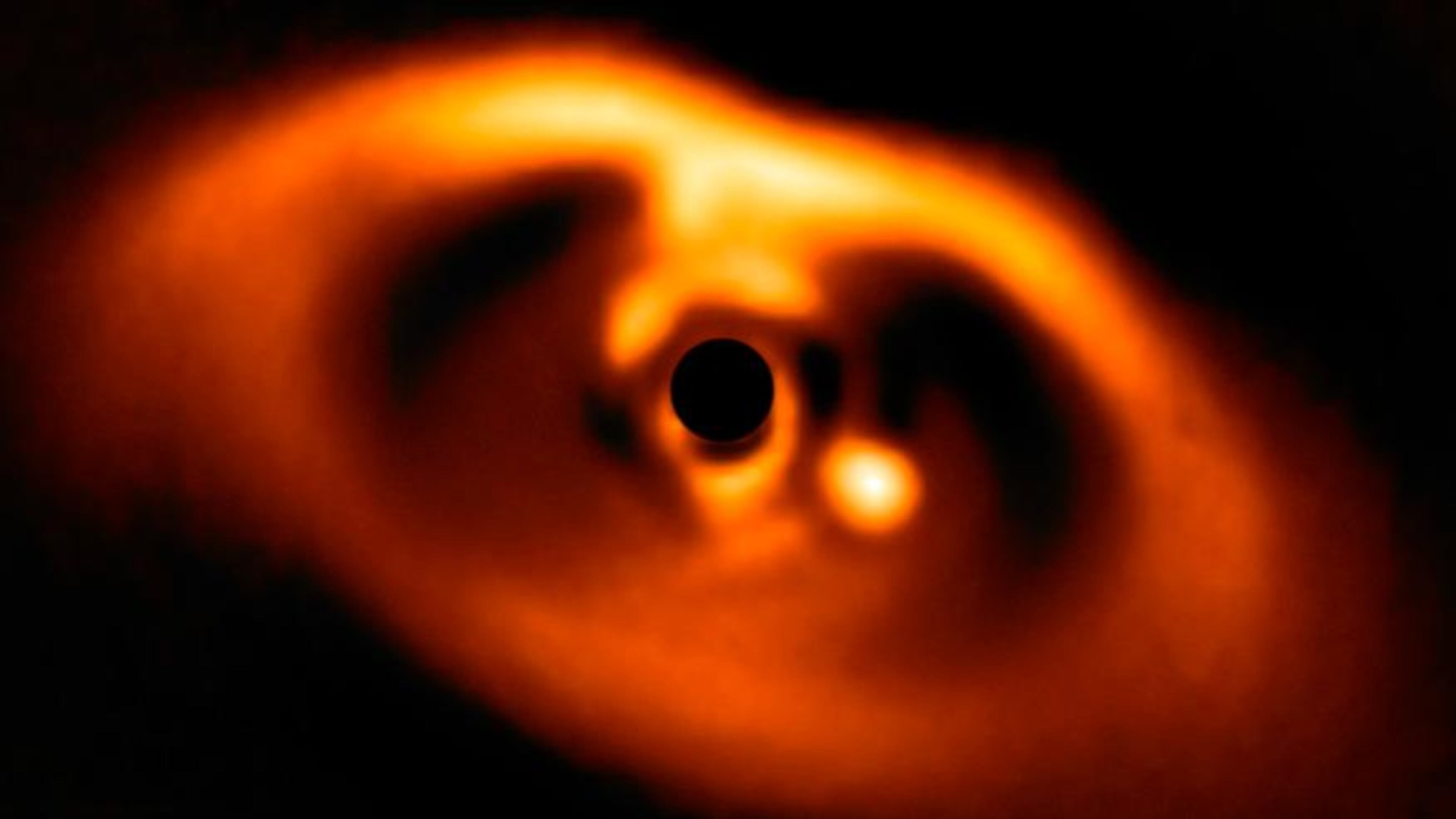 The photo provided by the European Southern Observatory ESO taken from the SPHERE instrument on ESO's Very Large Telescope is the first clear image of a planet caught in the very act of formation around the dwarf star PDS 70. The planet stands clearly out, visible as a bright point to the right of the centre of the image, which is blacked out by the coronagraph mask used to block the blinding light of the central star. (ESO via AP)