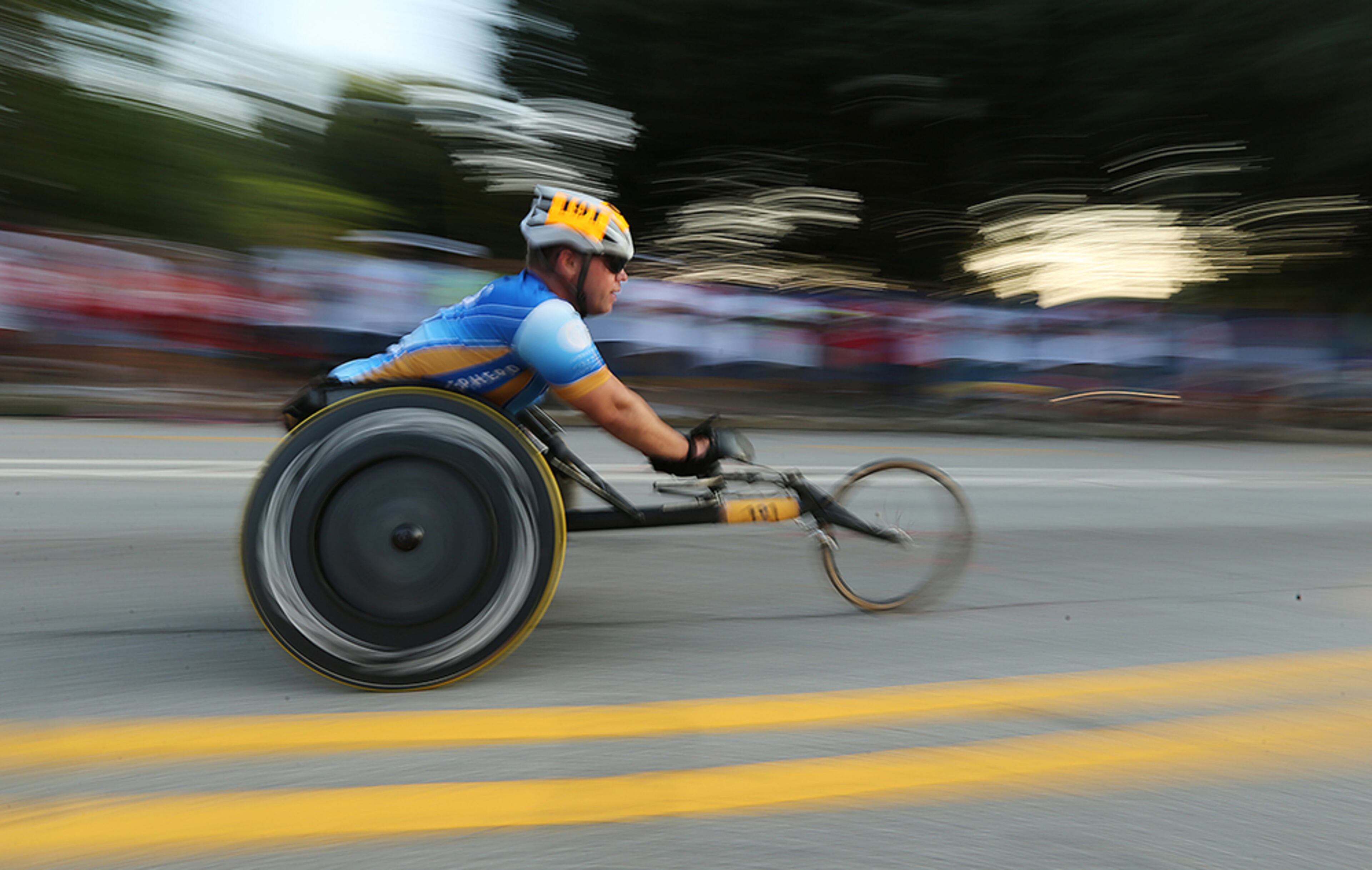 A wheelchair racer is a blur making his way down 10th street past the finish line in the 47th running of the AJC Peachtree Road Race at Piedmont Park on Monday, July 4, 2016, in Atlanta.