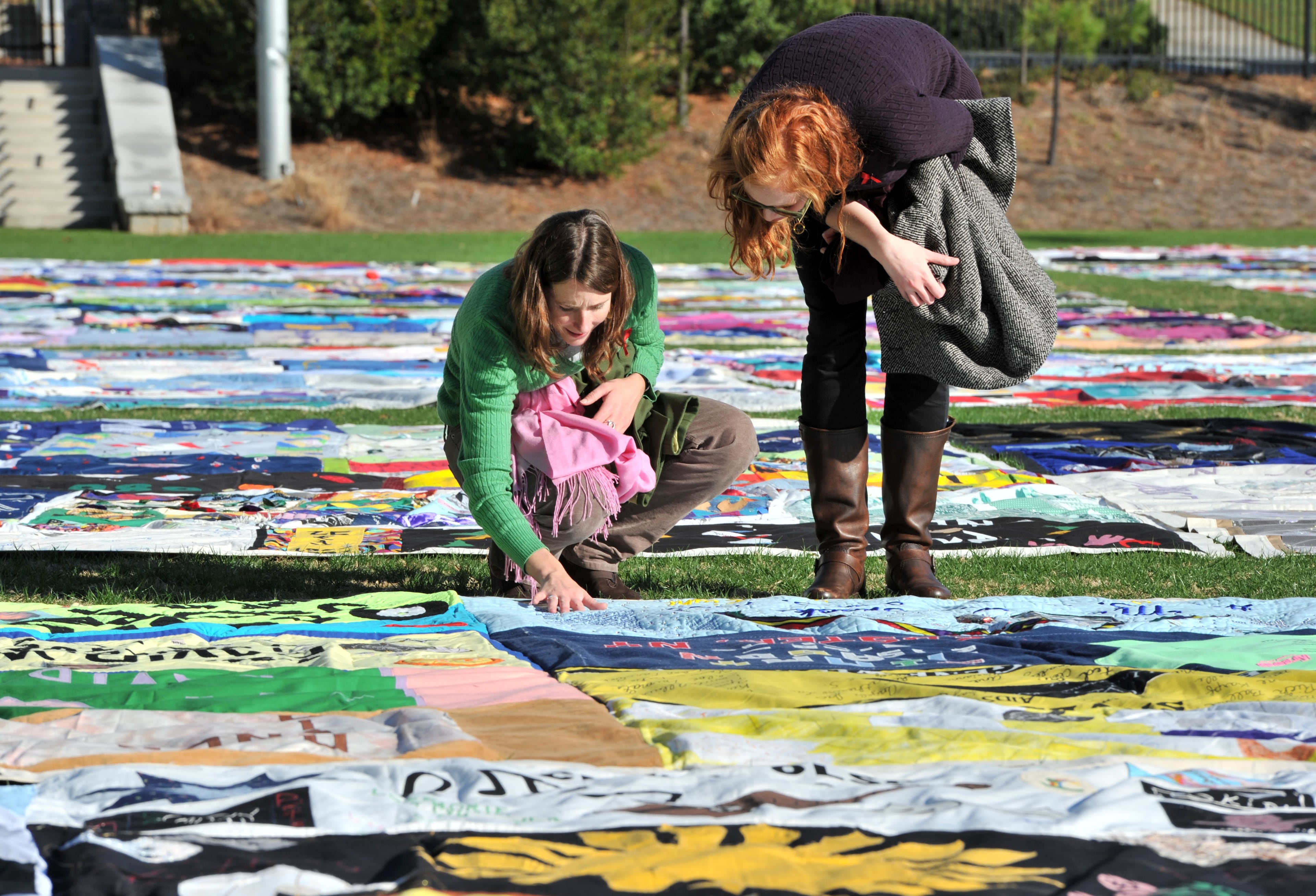 Kate Ogorzaly (left) touched one of AIDS Memorial Quilt displays as Ogorzally and Meg Bertram, then both graduate students majoring in Global Health, stop for a closer look at the AIDS Memorial Quilt. (Hyosub Shin/AJC)