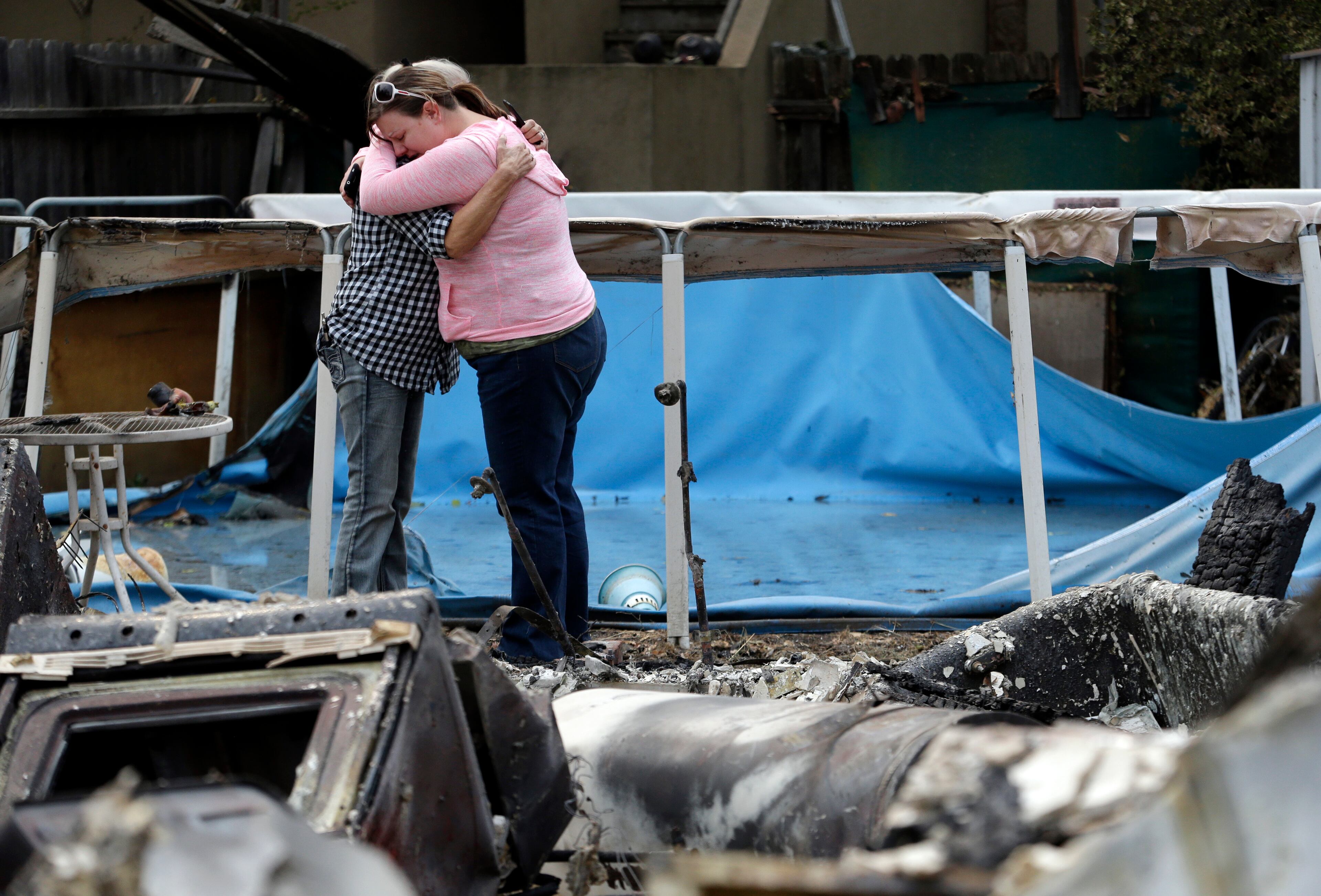 Deanna Hingst, right, embraces her mother Shirley Leuzinger as they stand at the family's destroyed home Monday, Sept. 14, 2015, in Middletown, Calif. Two of California's fastest-burning wildfires in decades overtook several Northern California towns, killing at least one person and destroying hundreds of homes and businesses and sending thousands of residents fleeing highways lined with buildings, guardrails and cars still in flames. (AP Photo/Elaine Thompson)