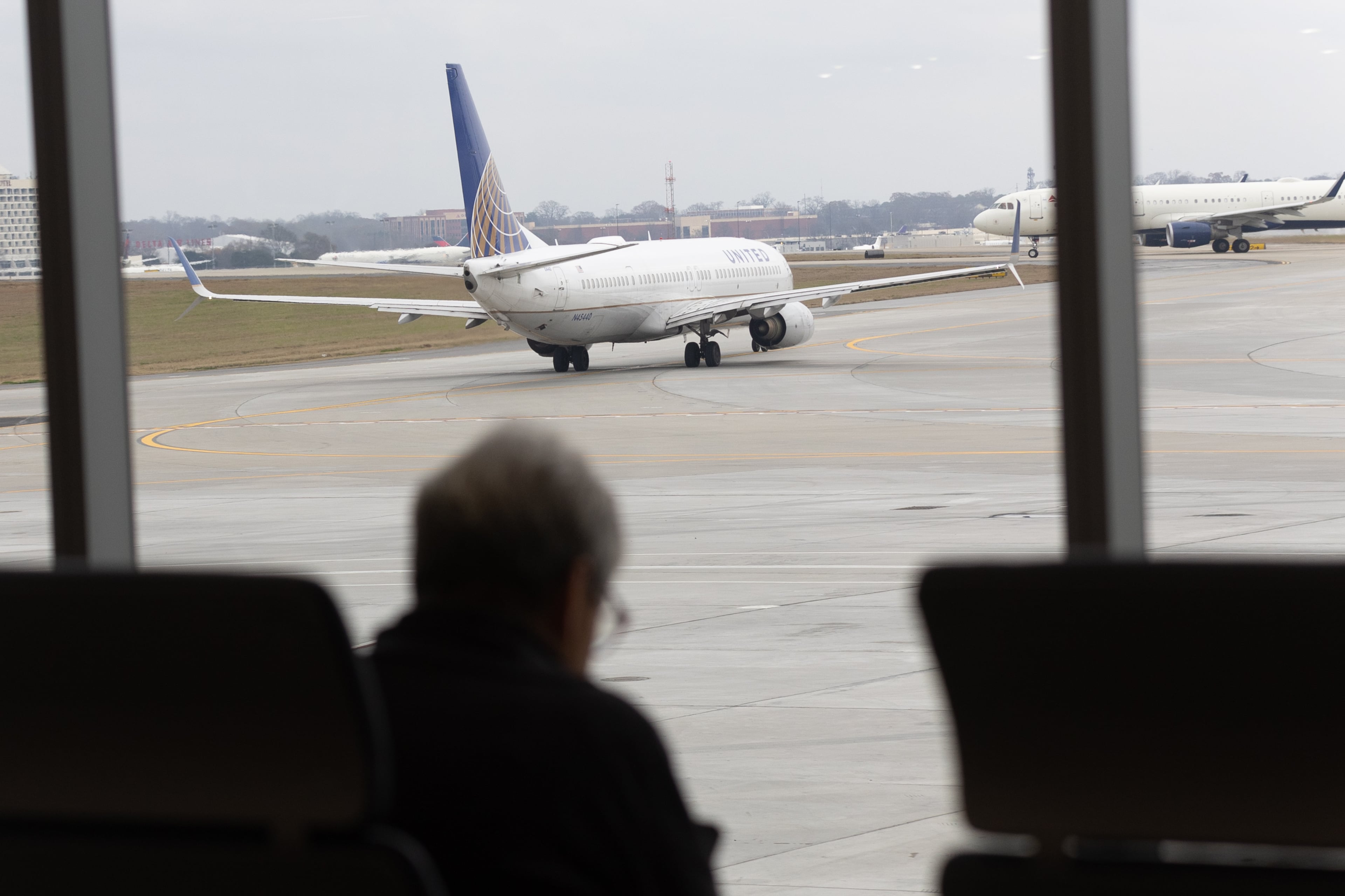 Travelers sit and watch jets depart in the new Concourse T extension at Hartsfield-Jackson Atlanta International Airport Tuesday, December 13, 2022. (Steve Schaefer/steve.schaefer@ajc.com)