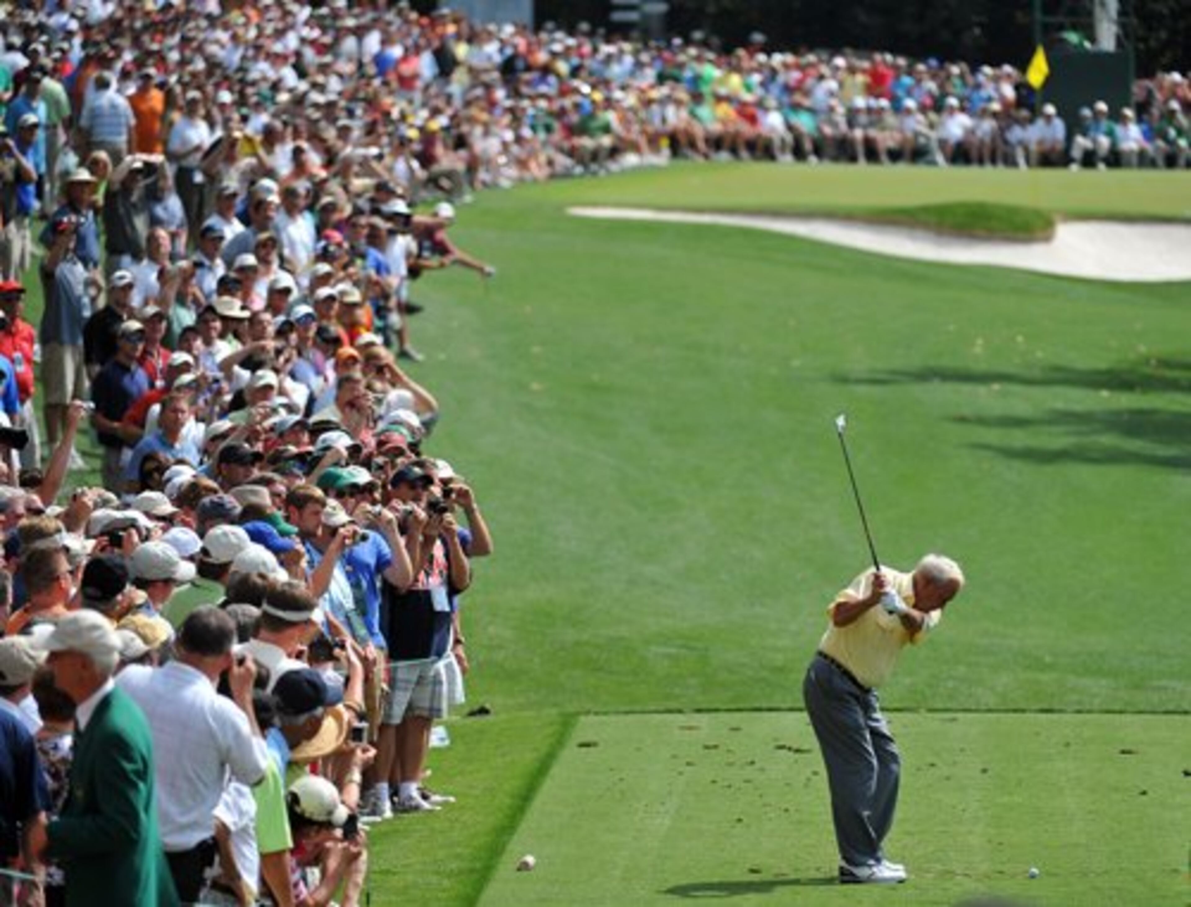 Four-time Masters champion Arnold Palmer still draws a crowd as he hits his tee shot on the 5 tee during the par three contest at Augusta National Wednesday April 7, 2010.