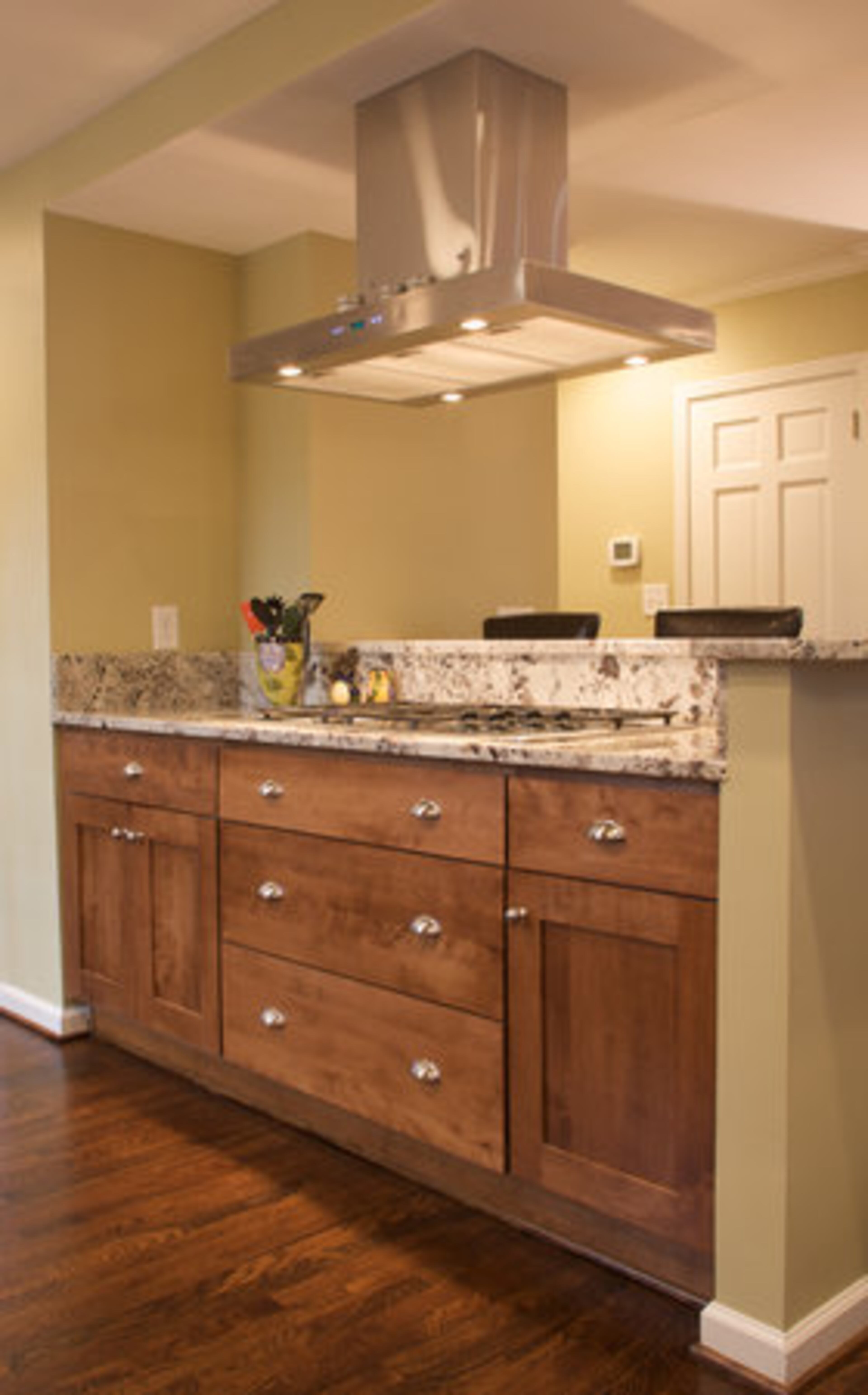 White Delicatus granite was added to create the counter for an eating area that the family uses regularly. The range was reused from the old home, but an updated modern hood system was installed in the remodeled kitchen.