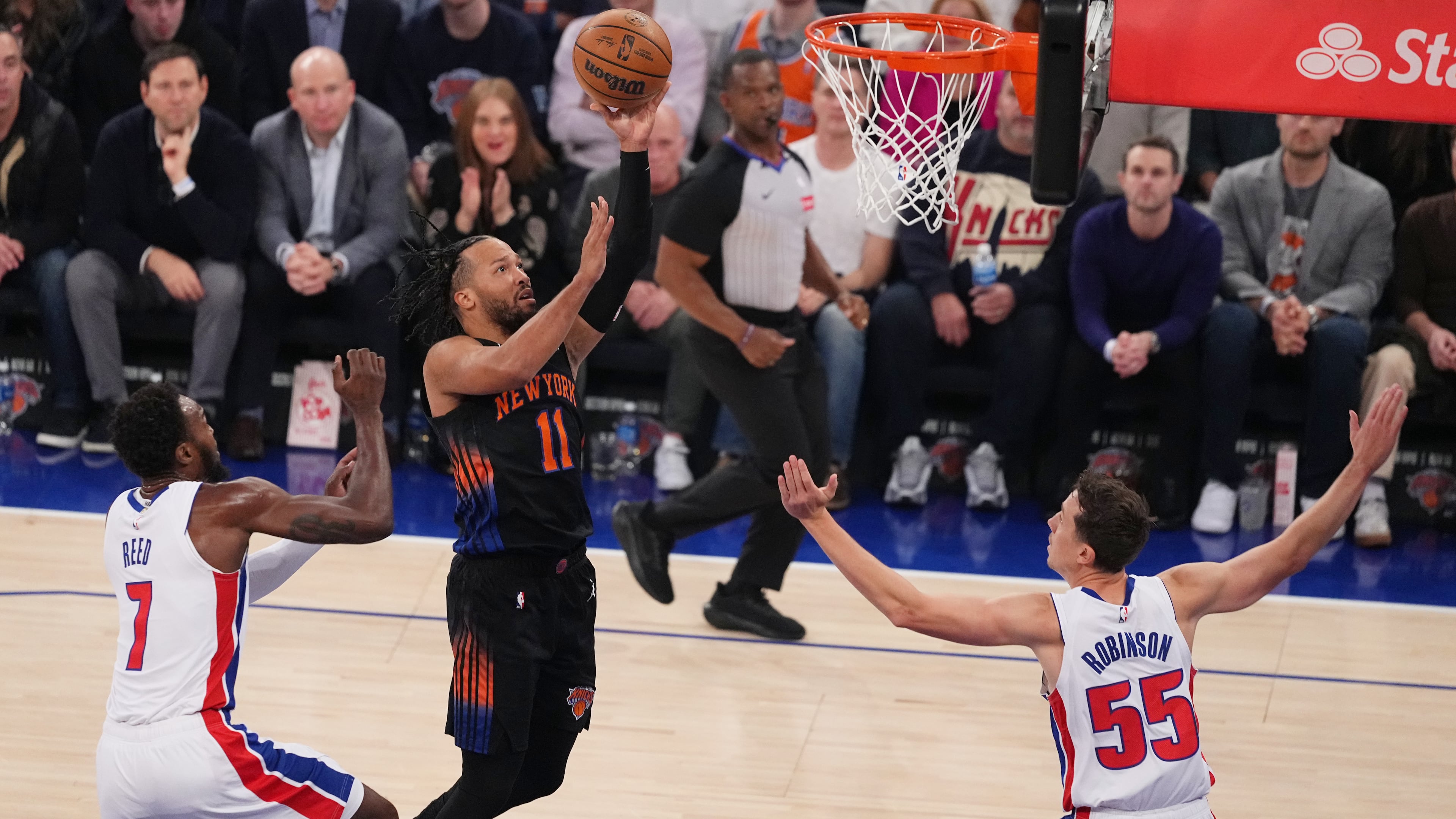 New York Knicks' Jalen Brunson (11) drives past Detroit Pistons' Paul Reed (7) and Duncan Robinson (55) during the first half of an NBA basketball game Tuesday, Oct. 27, 2026, in New York. (AP Photo/Frank Franklin II)