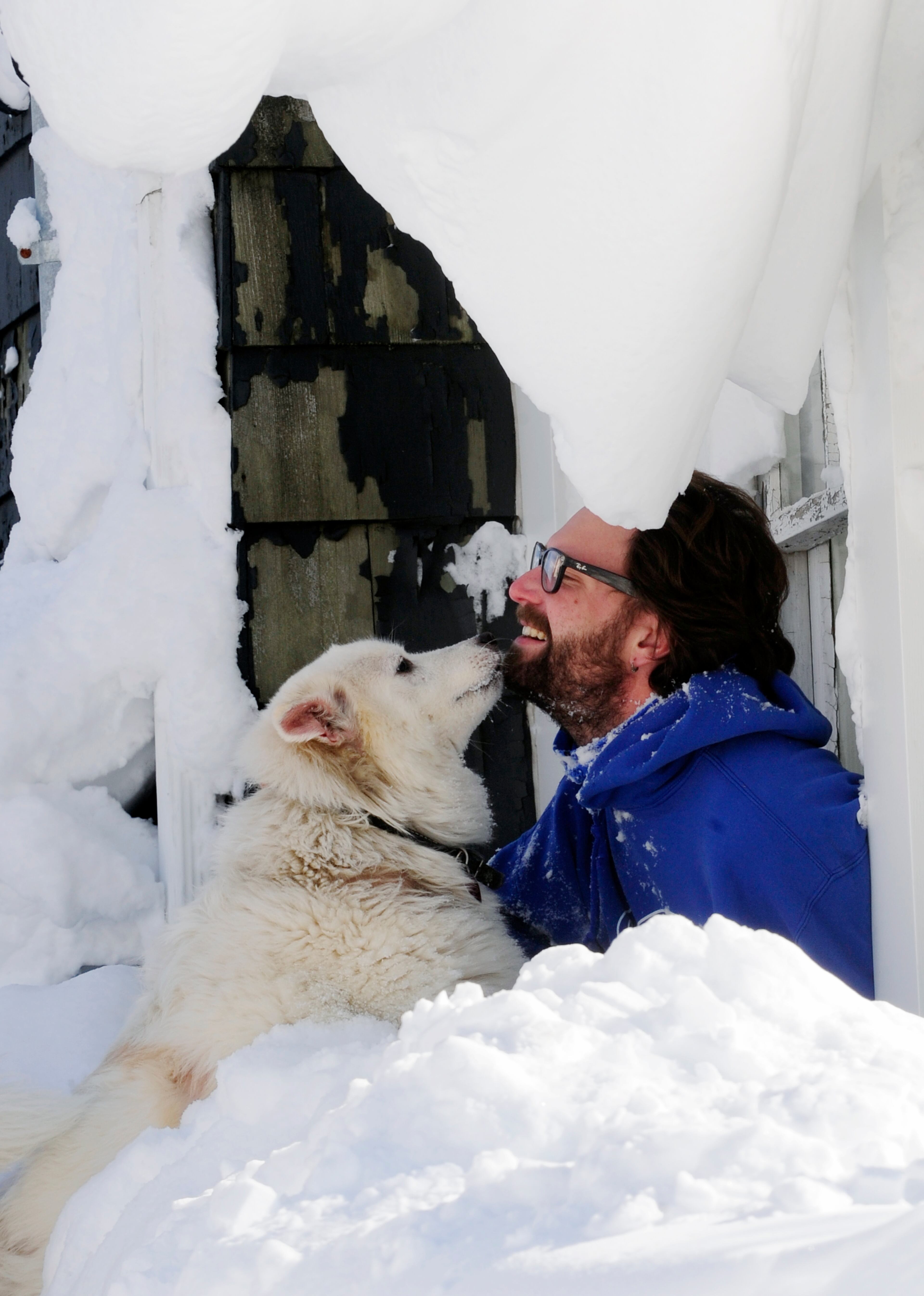 Steve Corbett opens his window under snow drifts and greets his neighbor's dog Wednesday, Nov. 19, 2014, on Central Avenue, in Lancaster, N.Y. A lake-effect snowstorm dumped over 5 feet of snow in areas across western New York. Another 2 to 3 feet of snow is expected in the area, bringing snow totals to over 100 inches, almost a year's worth of snow in three days. (AP photo/Gary Wiepert)