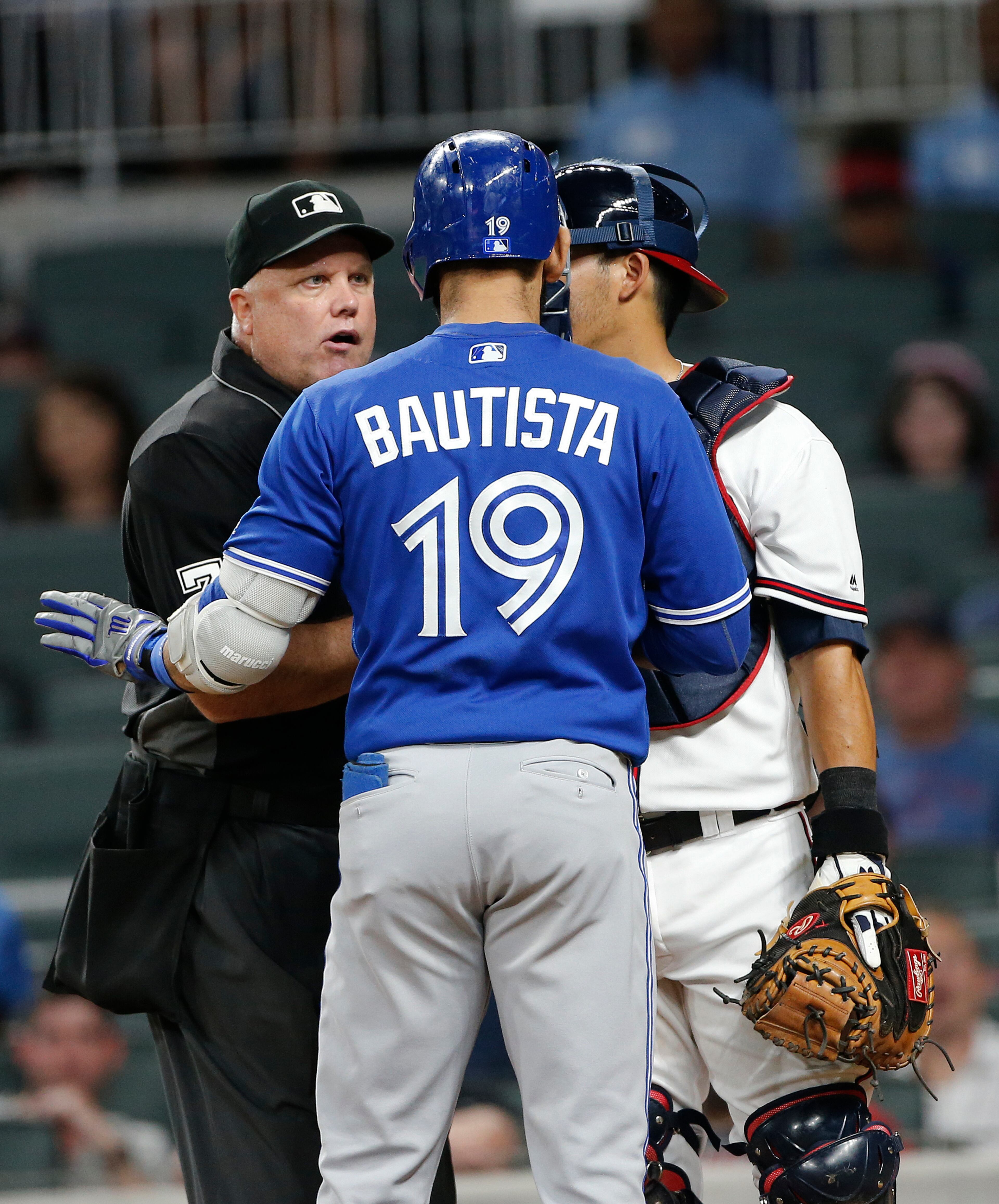 Umpire Brian O'Nora (7) steps between Toronto Blue Jays' Jose Bautista (19) and Atlanta Braves catcher Kurt Suzuki after they exchanged words following a Bautista home run during the eighth inning of a baseball game Wednesday, May 17, 2017, in Atlanta. Atlanta won 8-4. (AP Photo/John Bazemore)