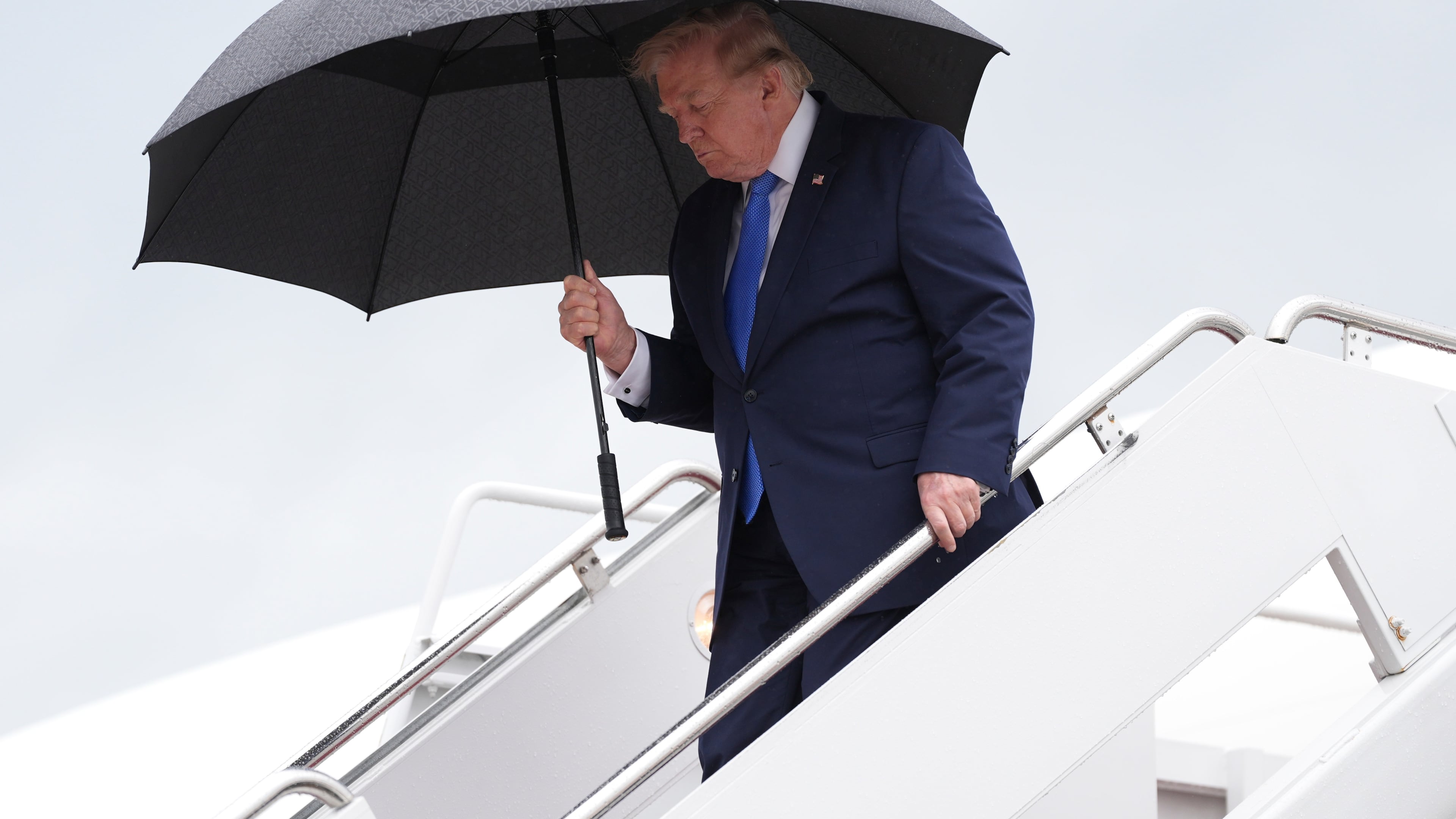 President Donald Trump carries an umbrella as he exits Air Force One at Joint Base Andrews, Md., Sunday, Aug. 2, 2026, on return to Washington. (AP Photo/Jacquelyn Martin)
