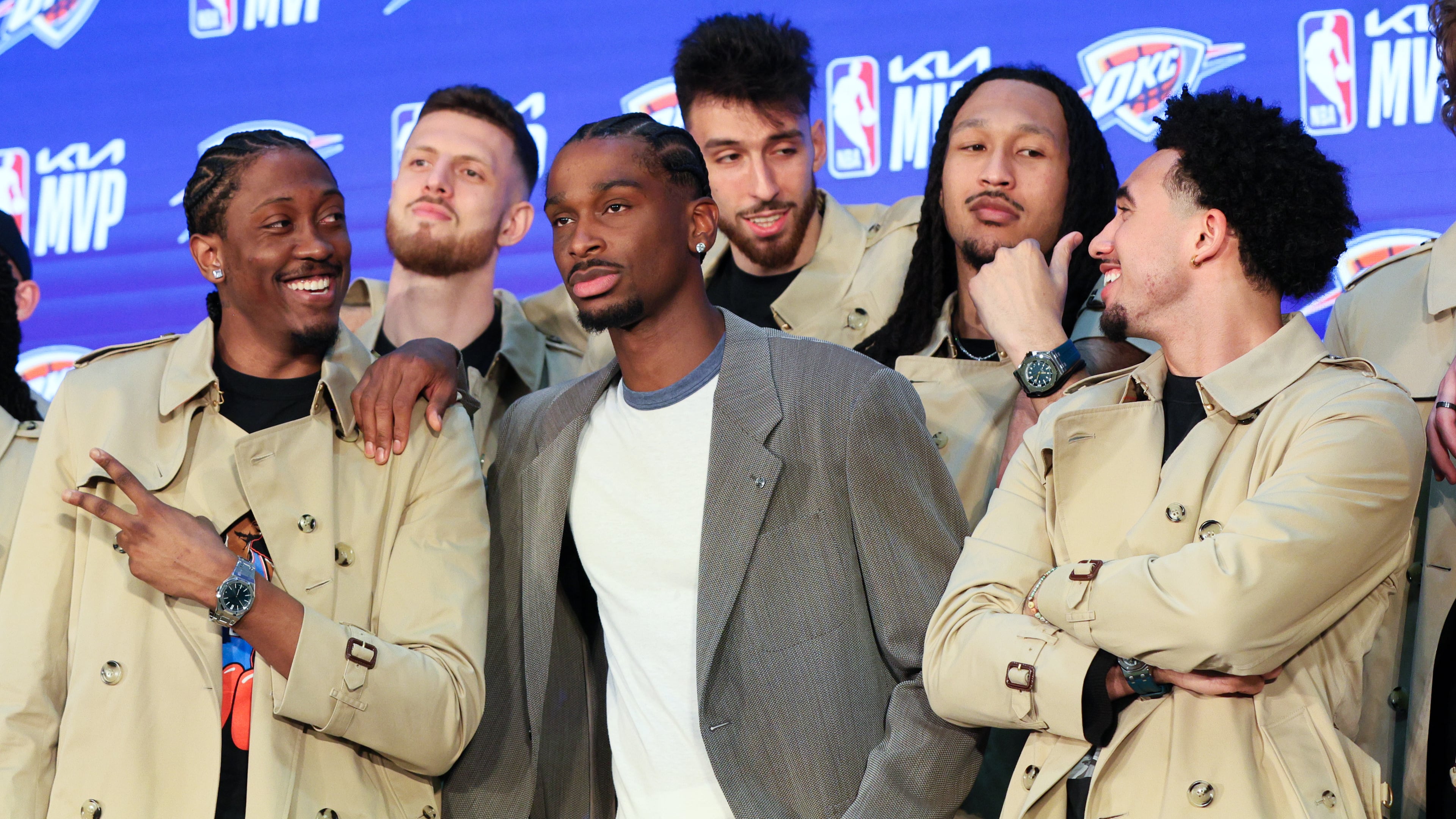 Oklahoma City Thunder guard Shai Gilgeous-Alexander, center, poses with teammates Jalen Williams, left, Isaiah Hartenstein, second from left, Chet Holmgren, center back, Jaylin Williams, second from right, and Jared McCain, right, in Burberry trench coats bought by Gilgeous-Alexander during a news conference after he was named the NBA basketball MVP, Sunday, May 17, 2026, in Oklahoma City. (AP Photo/Nate Billings)