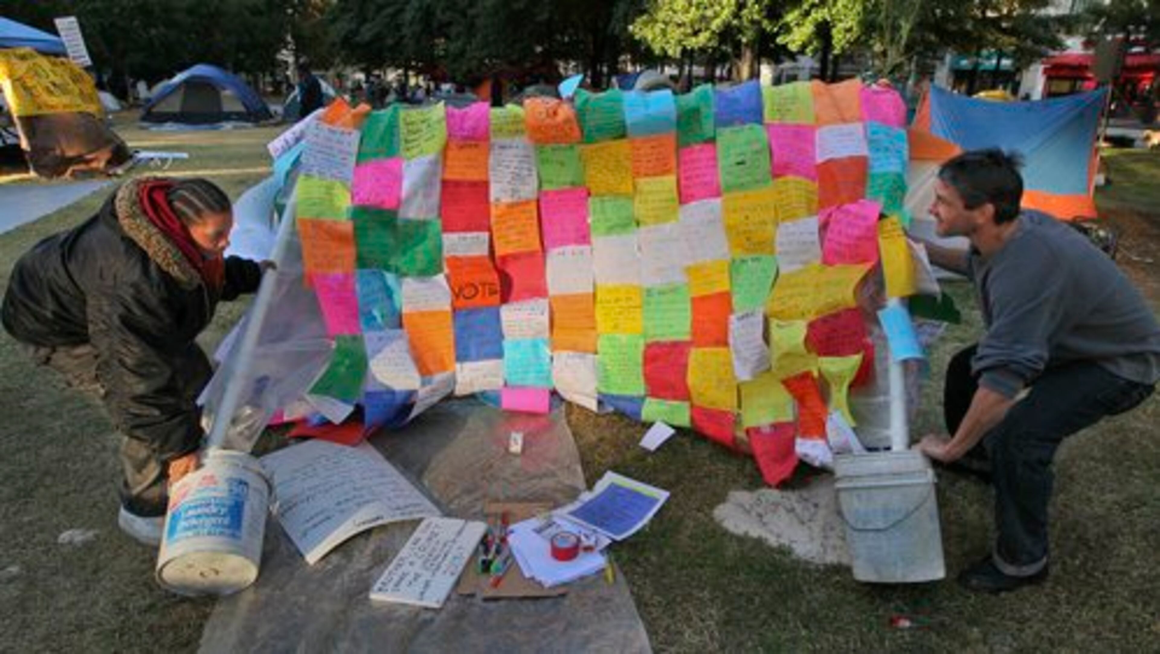 Joan Allen (left) and Tony Chase pick up a fallen board containing notes from Occupy Atlanta activists on Monday, Oct. 17, 2011 in Woodruff Park in Atlanta. About 100 activists woke up Monday with a deadline looming to have tents picked up by 5 p.m. and for all participants to be vacated from the park out of the park by 11 p.m.