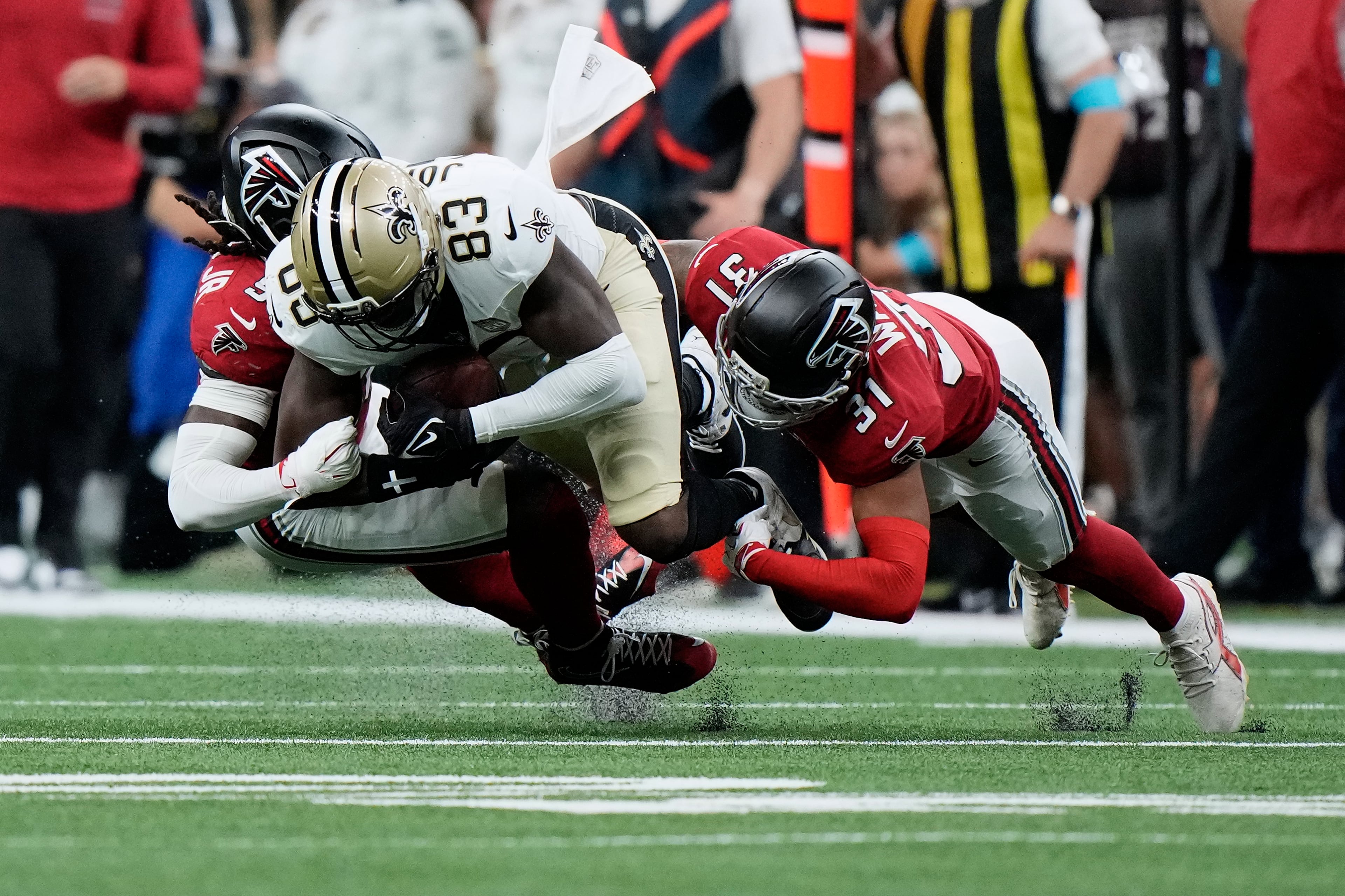 New Orleans Saints tight end Juwan Johnson is tackled by Atlanta Falcons linebacker Harold Perkins Jr. (left) and safety Xavier Watts (right) during the first half of an NFL football game in New Orleans, Monday, Oct. 5, 2026. (Gerald Herbert/AP)