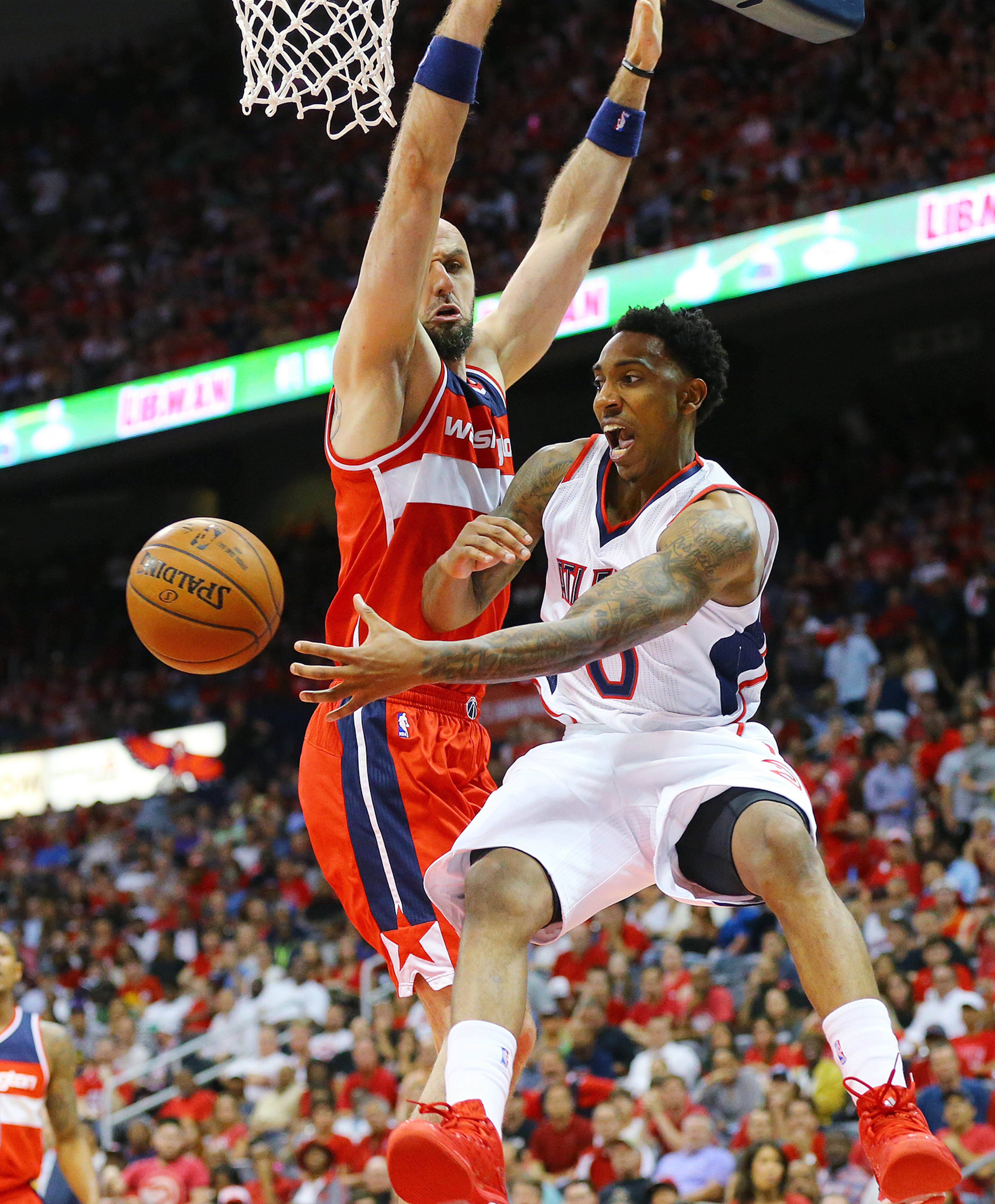 Hawks Jeff Teague passes off under the basket as Wizards Marcin Gortat defends in their Eastern Conference Semifinals game 5 on Tuesday, May 13, 2015, in Atlanta. Curtis Compton / ccompton@ajc.com