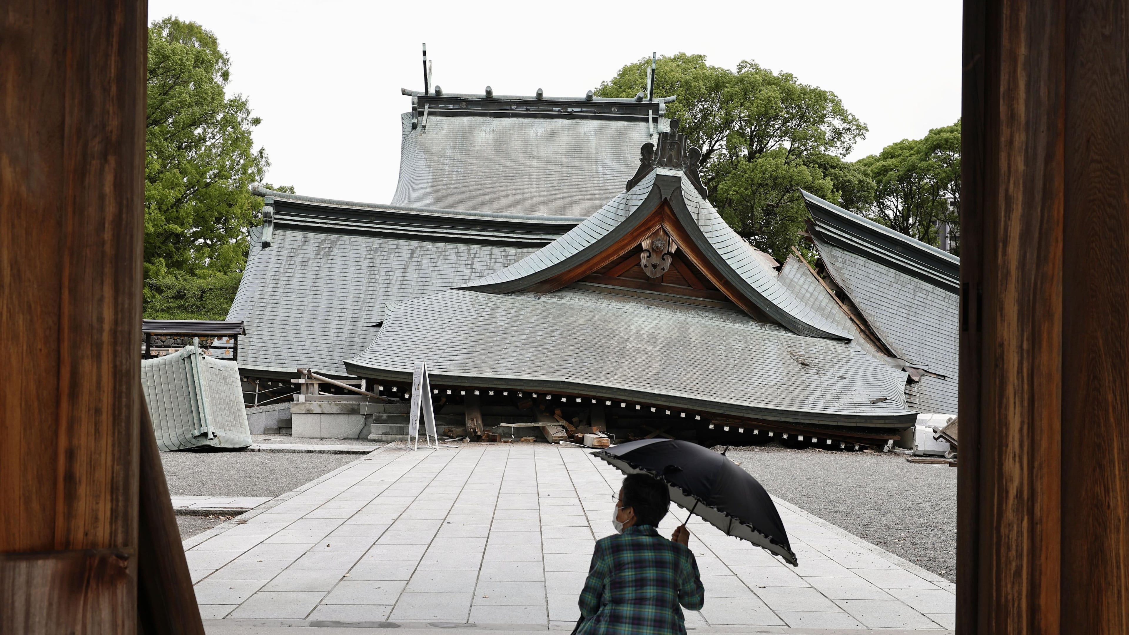 A visitor looks at the fallen roofs of the Yatsuhiro Shrine, a day after an earthquake in Yatsushiro, Kumamoto prefecture, Wednesday, July 29, 2026.(Juntaro Yokoyama/Kyodo News via AP)