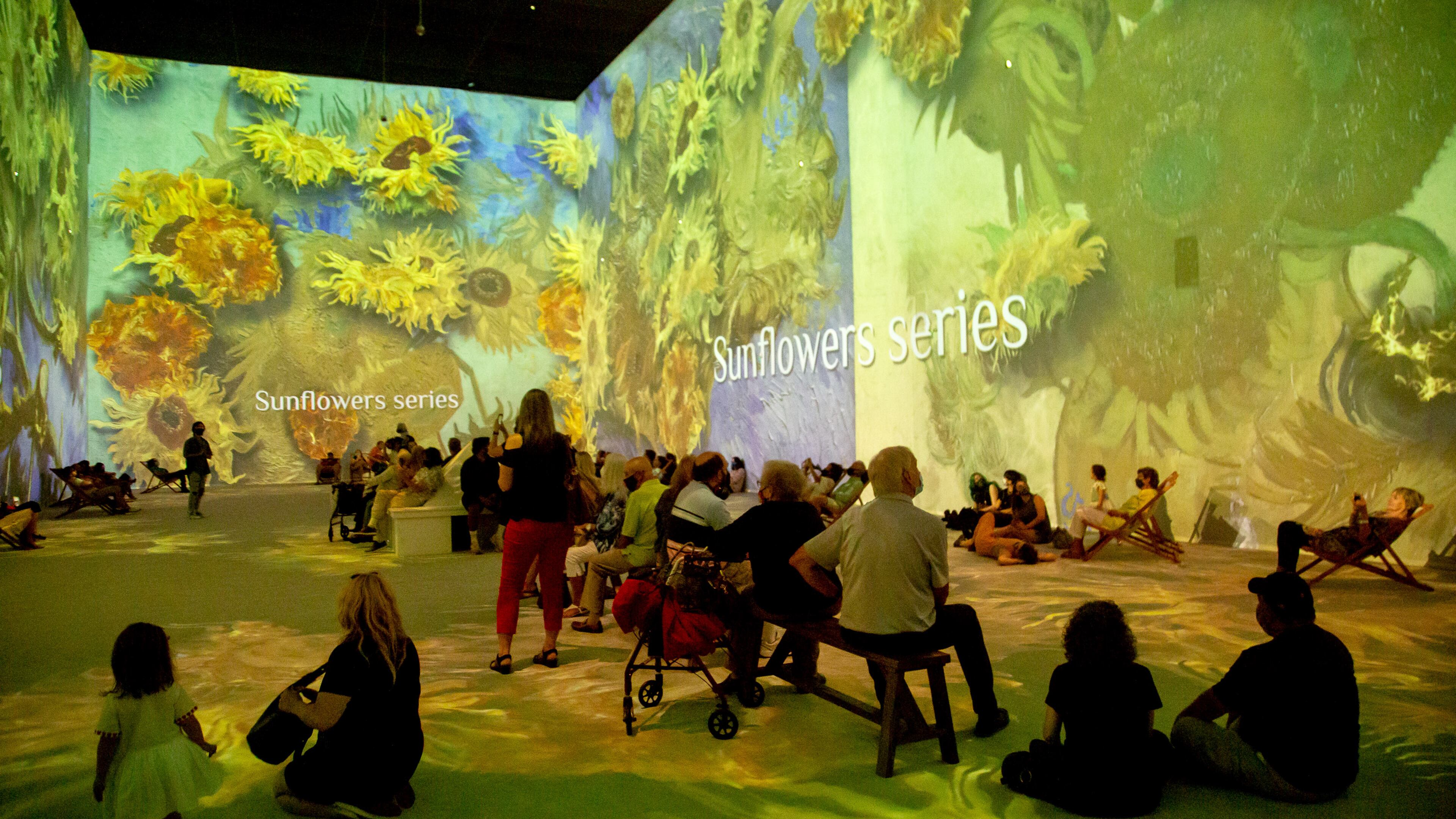 People sit and watch the two-story projections during the Van Gogh: The Immersive Experience at the Pullman Yard in Atlanta Thursday, May 20, 2021. STEVE SCHAEFER FOR THE ATLANTA JOURNAL-CONSTITUTION