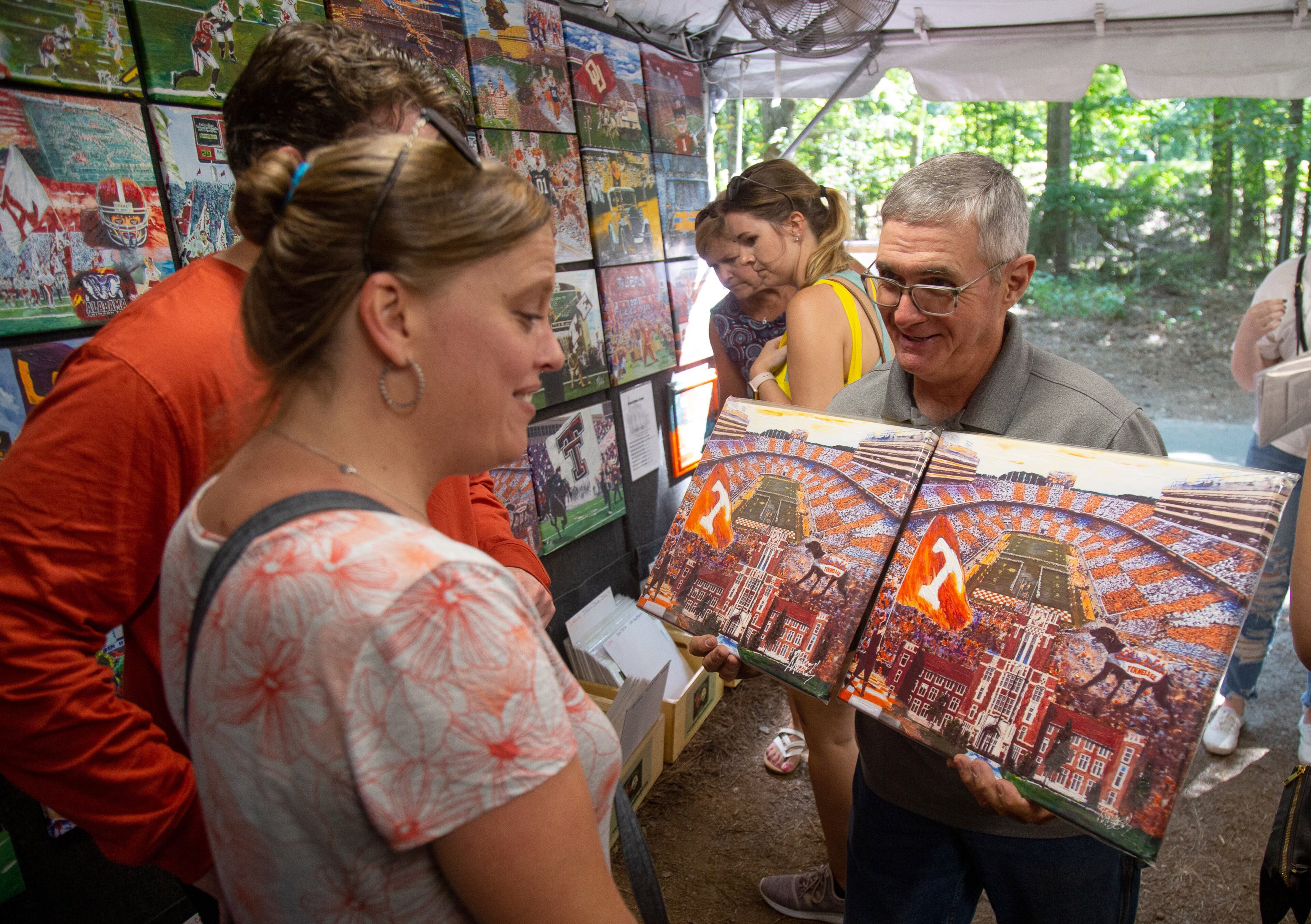 Bill Parker shows customers a painting during the 51st annual Yellow Daisy Festival at Stone Mountain Park on Sunday, September 8, 2019. STEVE SCHAEFER / SPECIAL TO THE AJC