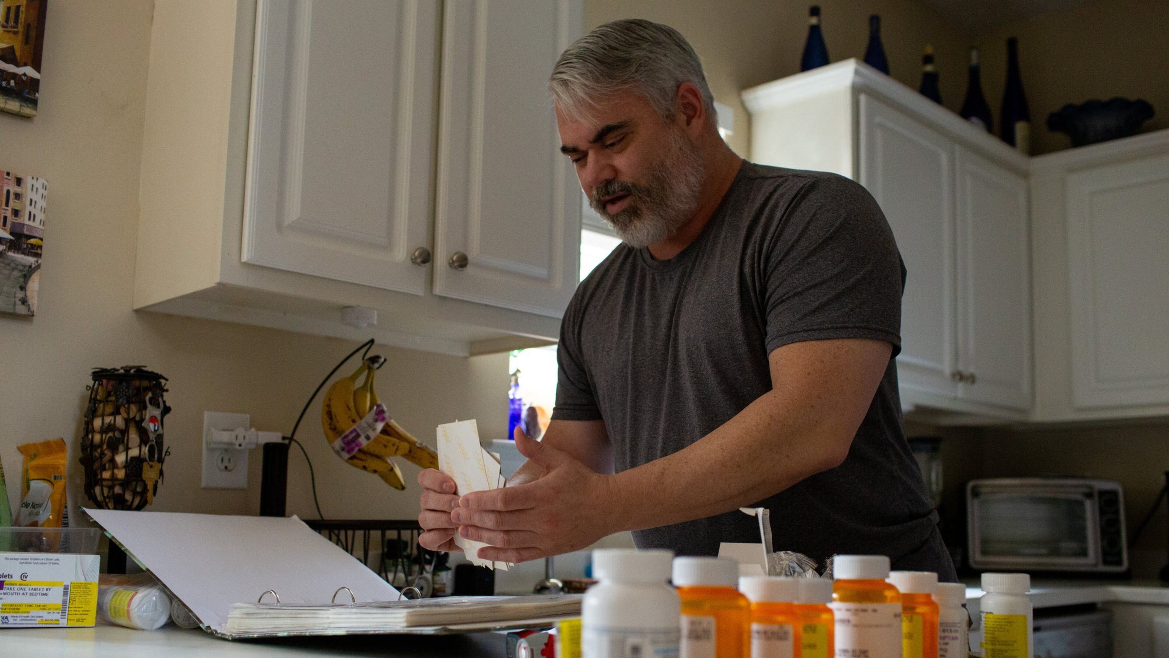 Bruce Barber sifts through photos from his deployment during the Gulf War in his home in Kennesaw. Barber has had problems getting medical appointments despite the MISSION Act, a new law that is supposed to help veterans get better, faster care outside of the VA system. It took Barber, a retired veteran from the Gulf War, 52 days to get a consultation on his war-injured neck because of fumbles and delays. (Photo/Rebecca Wright for the AJC)