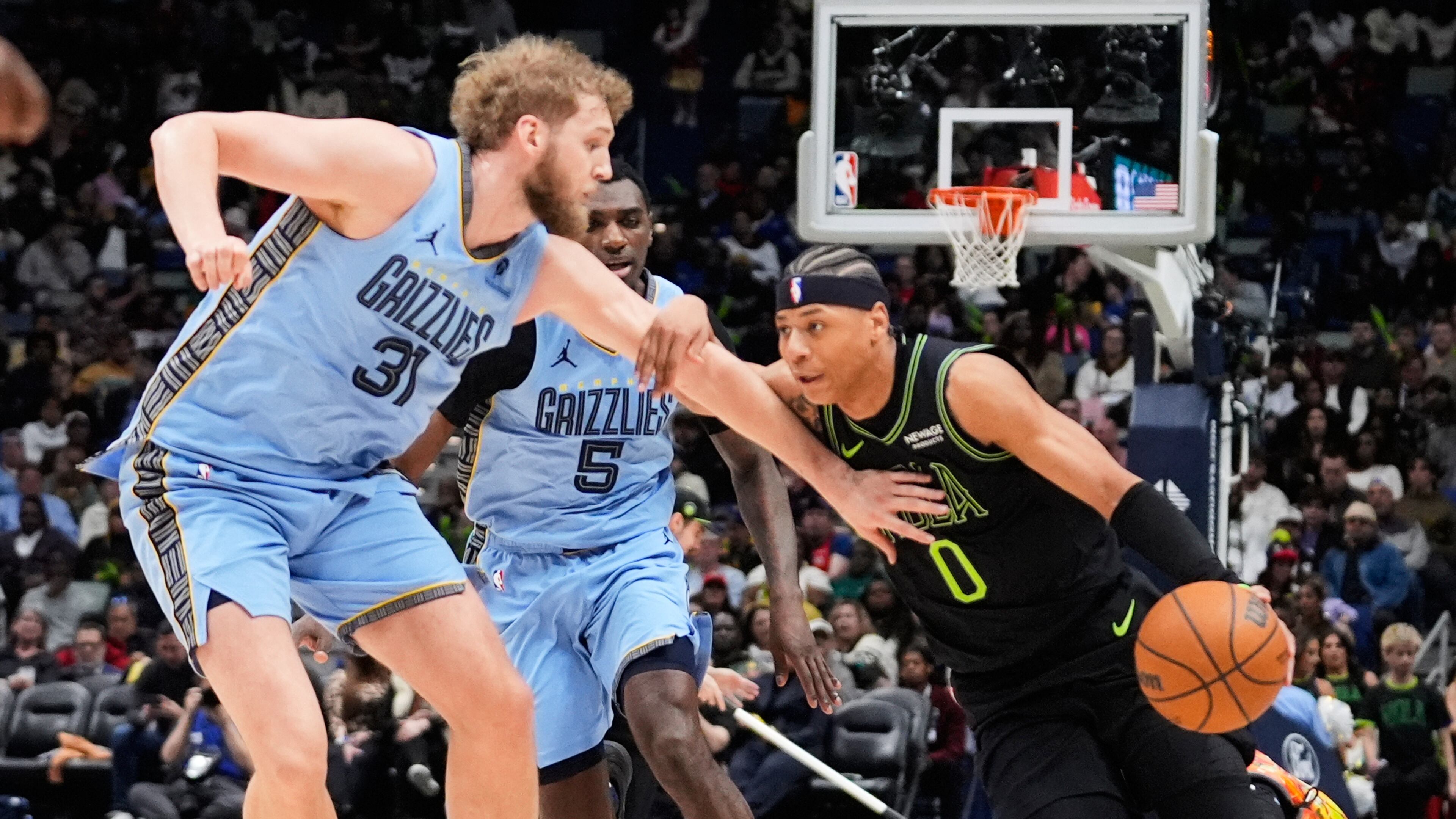 New Orleans Pelicans guard Jeremiah Fears (0) drives to the basket against Memphis Grizzlies center Jock Landale (31) and guard Vince Williams Jr. (5) in the first half of an NBA basketball game, Friday, Jan. 30, 2026, in New Orleans. (AP Photo/Avery Sikes)
