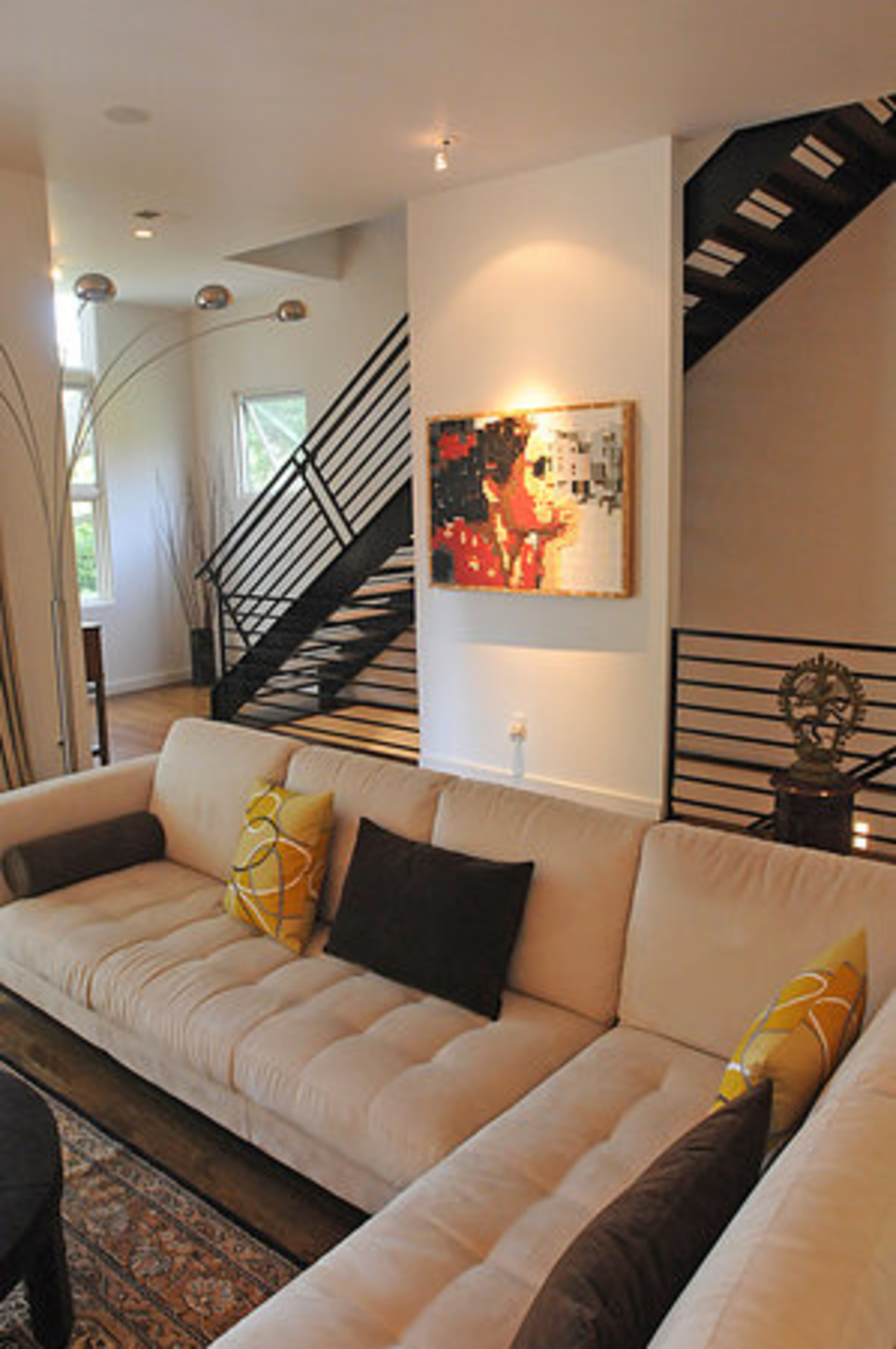 The spacious living room is light and airy with a primarily neutral color scheme with tasteful pops of color. Modern and abstract art is used to accent rooms throughout their home.