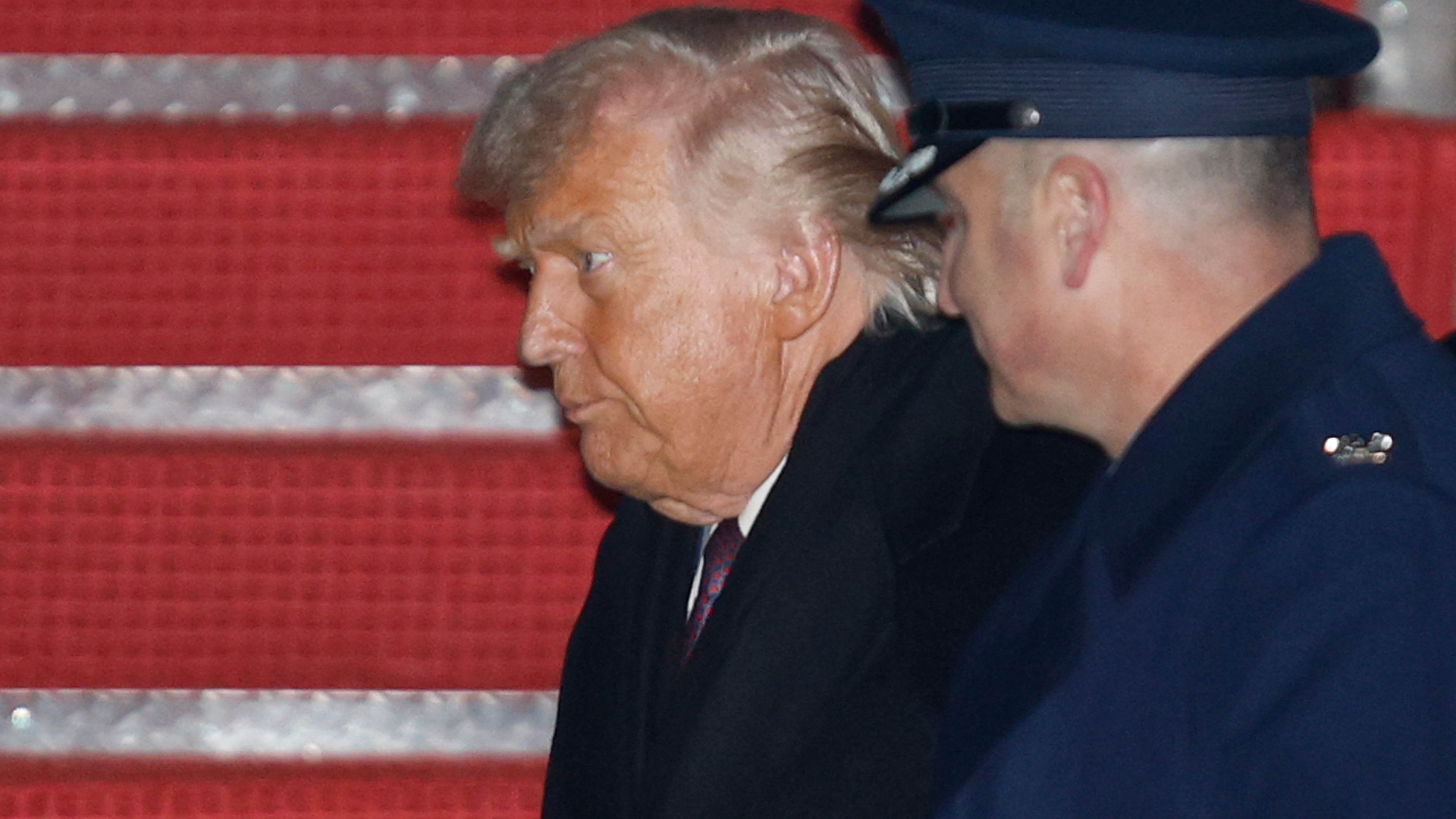 President Donald Trump, left, is greeted by Air Force Col. Christopher M. Robinson, commander of the 89th Airlift Wing, right, after walking down the stairs of Air Force One, upon his arrival at Joint Base Andrews, Md., Thursday, Jan. 22, 2026, after returning from the World Economic Forum in Davos, Switzerland.(AP Photo/Luis M. Alvarez)