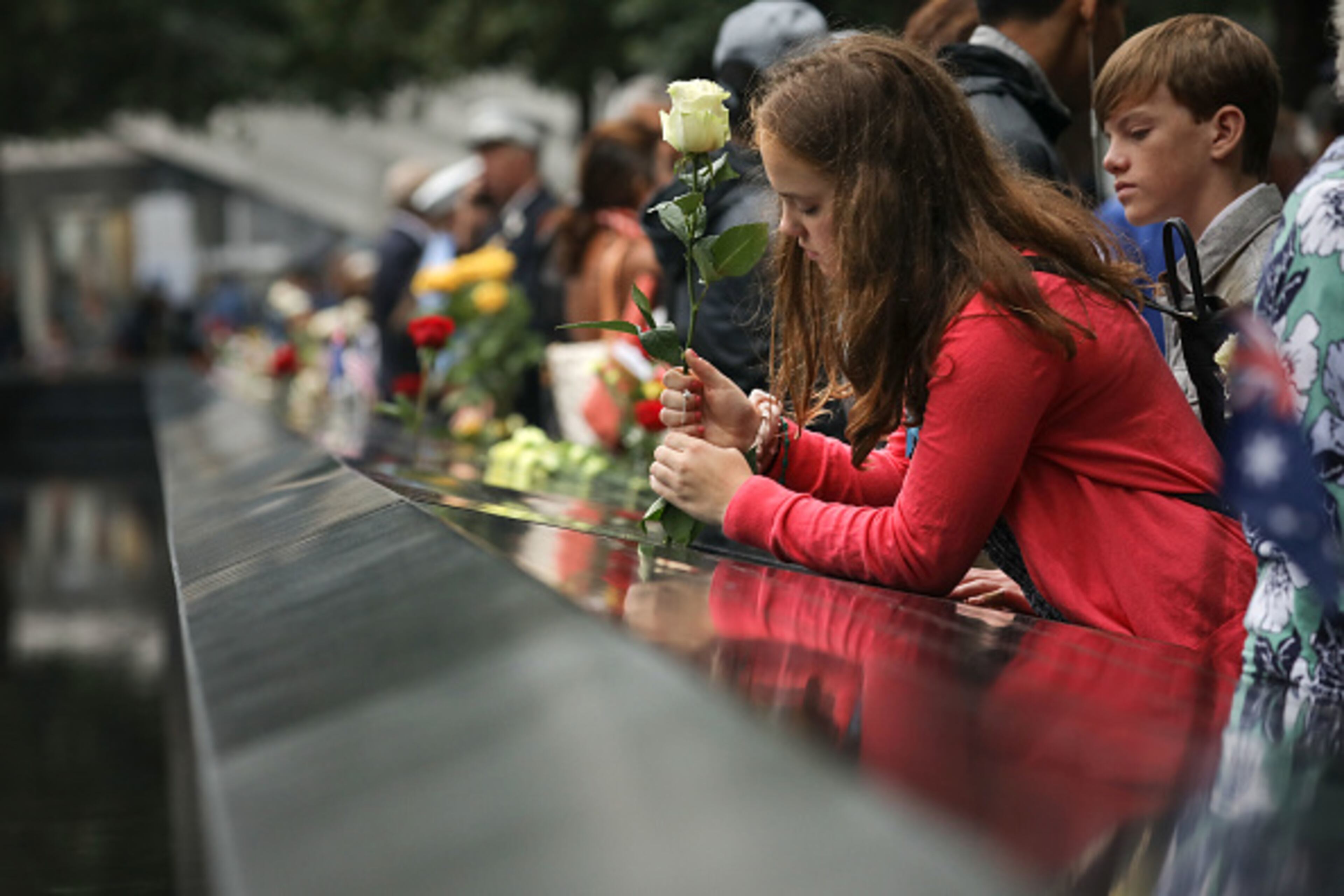 NEW YORK, NY - SEPTEMBER 11: A girl places a flower along the north pool during a commemoration ceremony for the victims of the September 11 terrorist attacks at the National September 11 Memorial, September 11, 2018 in New York City. In New York City and throughout the United States, the country is marking the 17th anniversary of the September 11 terrorist attacks. (Photo by Drew Angerer/Getty Images)