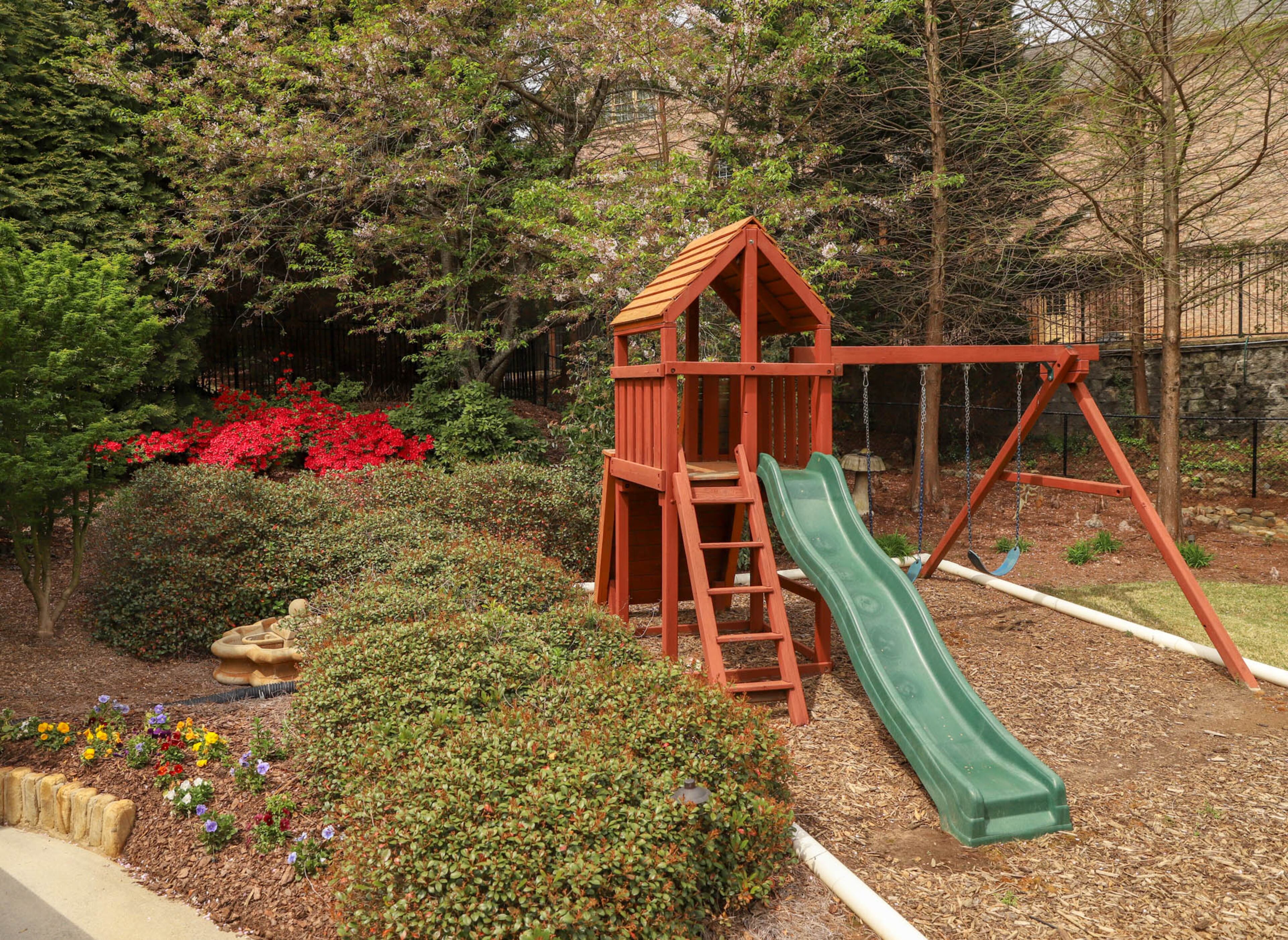 A playset from PlayNation is nestled in a portion of the yard.