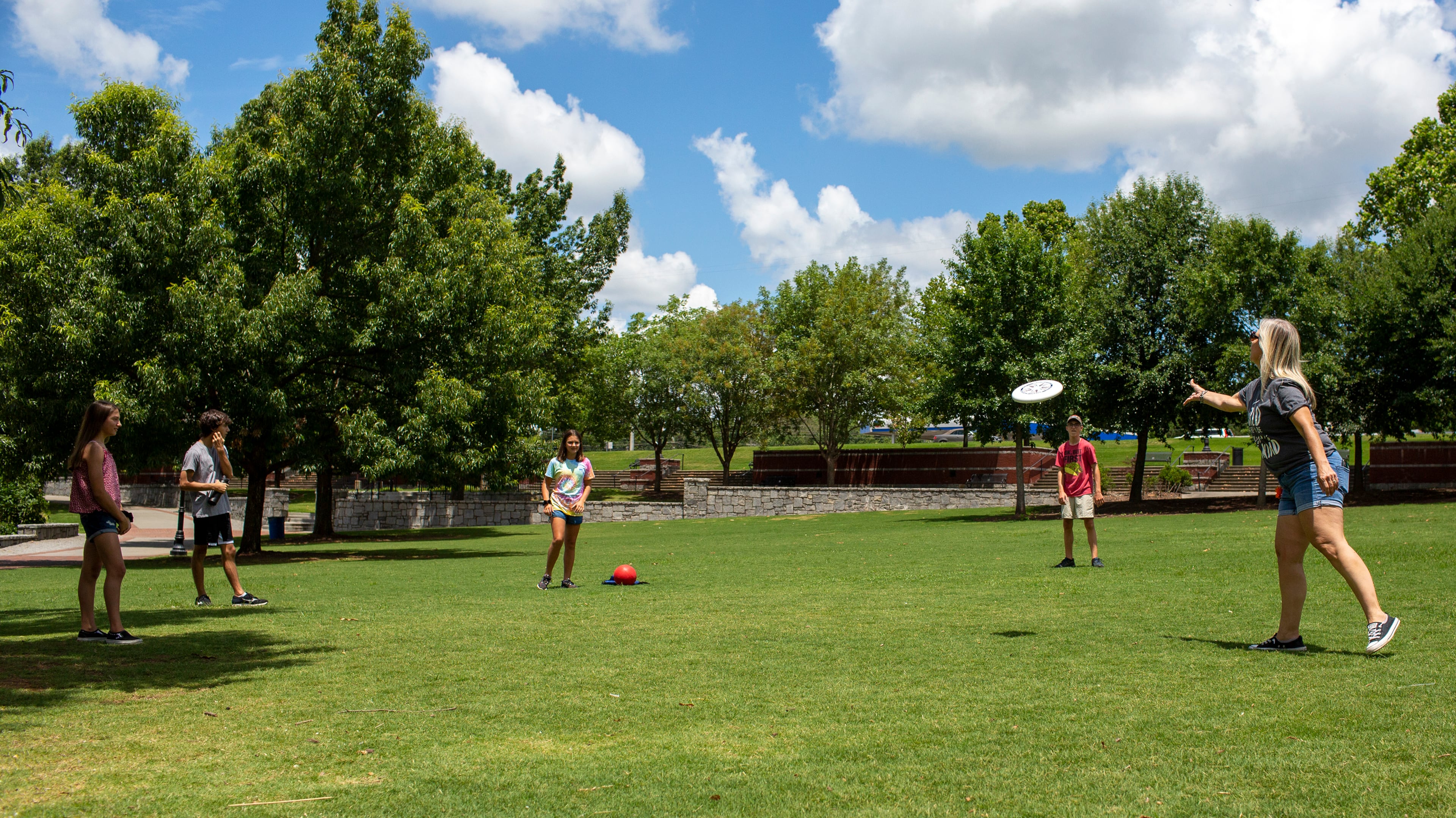 A family plays frisbee in Suwanee Town Center Park in Suwanee, Georgia, on Wednesday, July 8, 2020. (REBECCA WRIGHT FOR THE ATLANTA JOURNAL-CONSTITUTION)