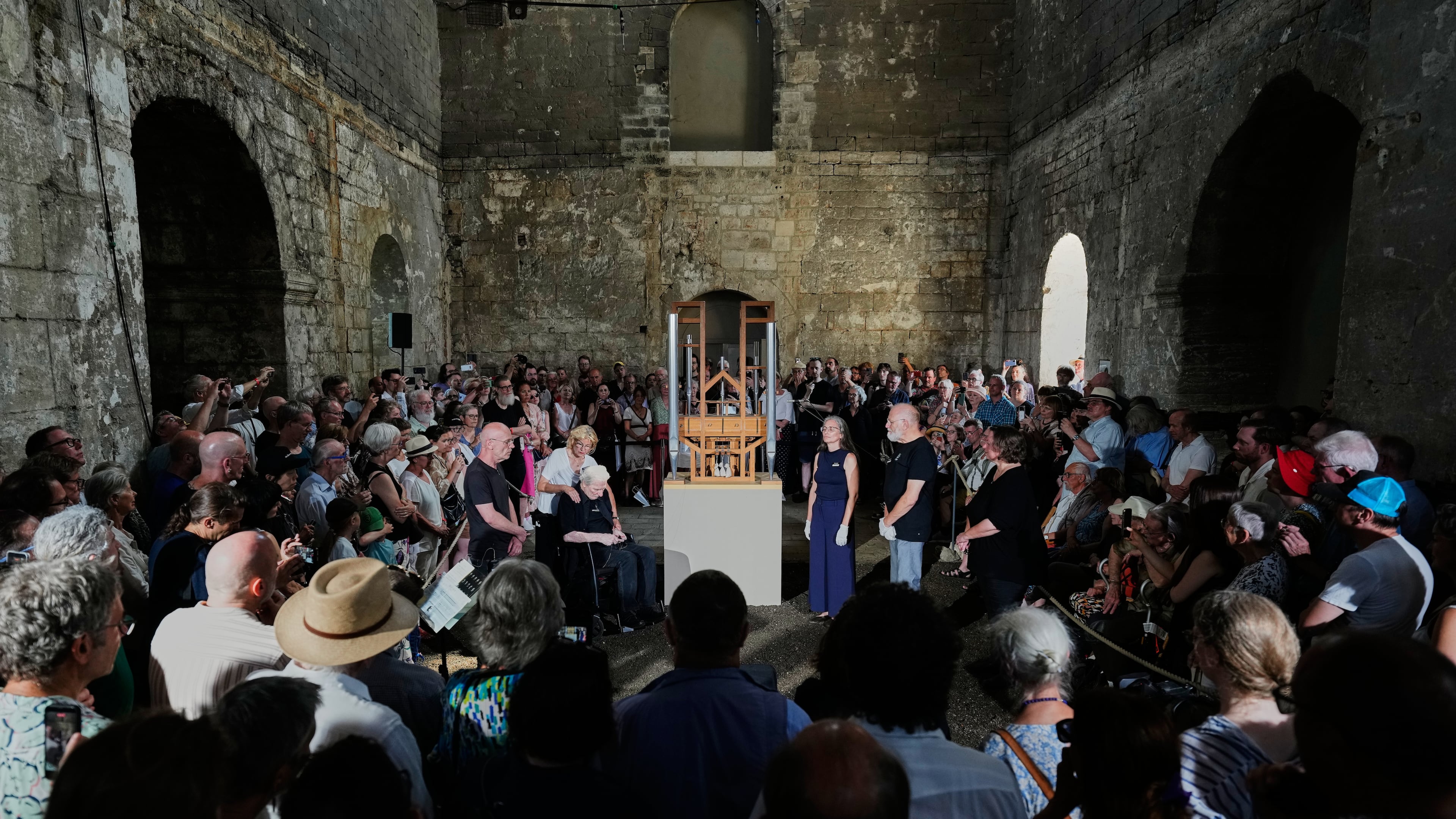 People listen to the sound of the John Cage Organ Project Halberstadt during a chord change of the organ inside the medieval Burchardi Church in Halberstadt, Germany, Wednesday, Aug. 5, 2026. (AP Photo/Markus Schreiber)