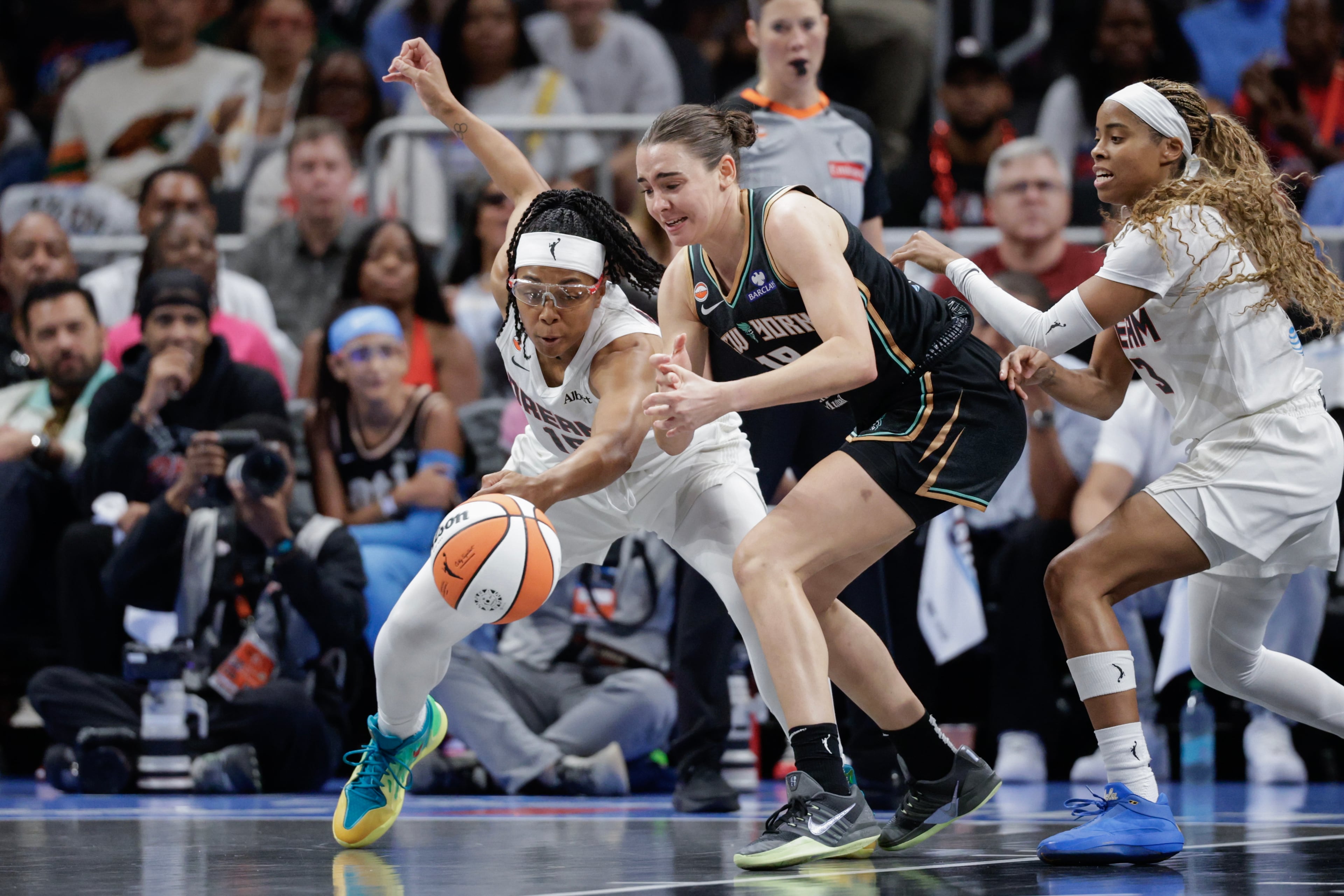 Atlanta Dream guards Allisha Gray, left, and Jordin Canada (3) defend against New York Liberty guard Pauline Astier, center, during the first half of a WNBA semifinal playoff game 1 between the Atlanta Dream and the New York Liberty, Sunday, Oct. 4, 2026, in Atlanta. (Erik S. Lesser for the AJC)