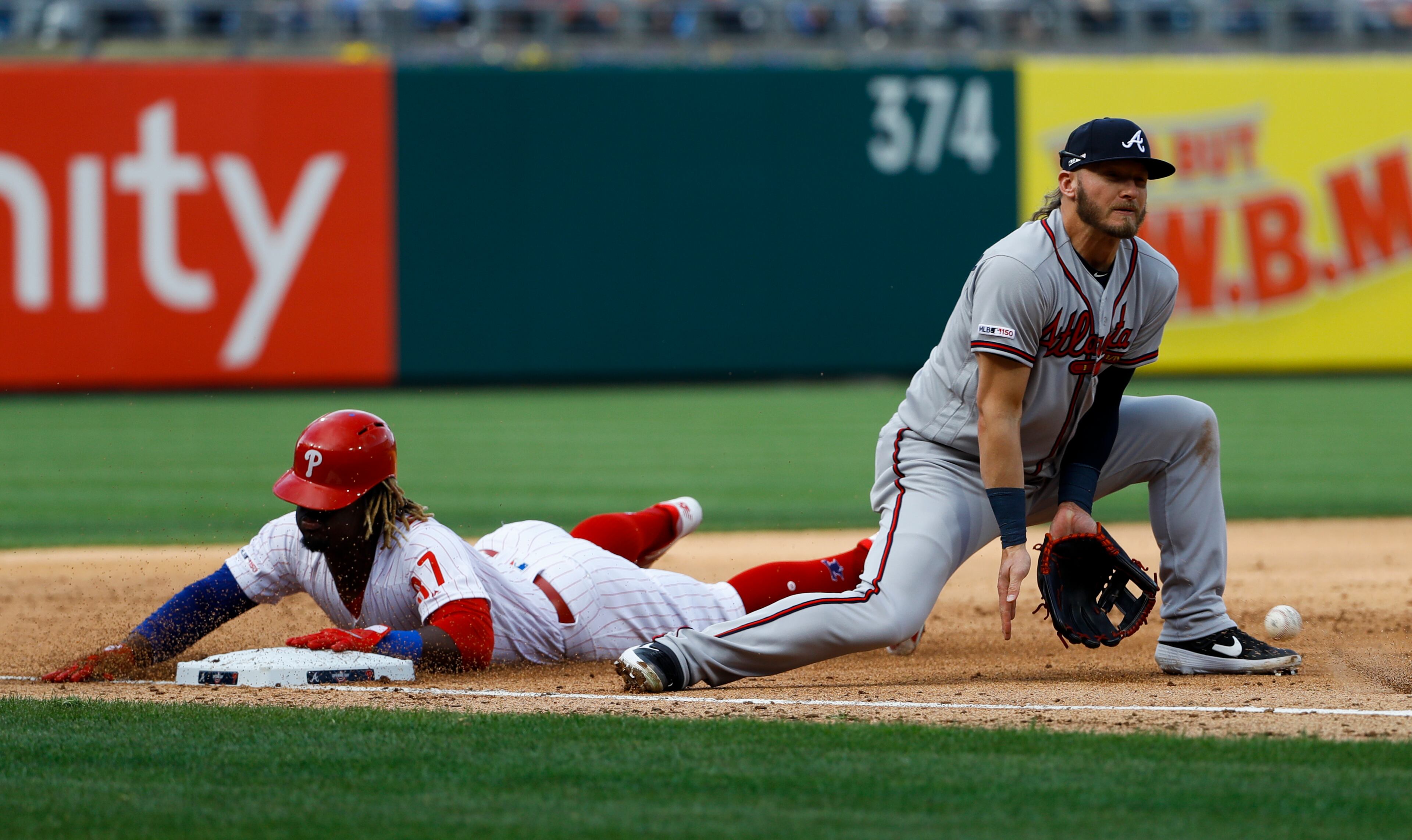 Philadelphia Phillies' Odubel Herrera slides into third base on a wild pitch by Atlanta Braves starting pitcher Julio Teheran as third baseman Josh Donaldson digs out the throw from home during the fourth inning of an opening day baseball game, Thursday, March 28, 2019, in Philadelphia. (AP Photo/Matt Slocum)