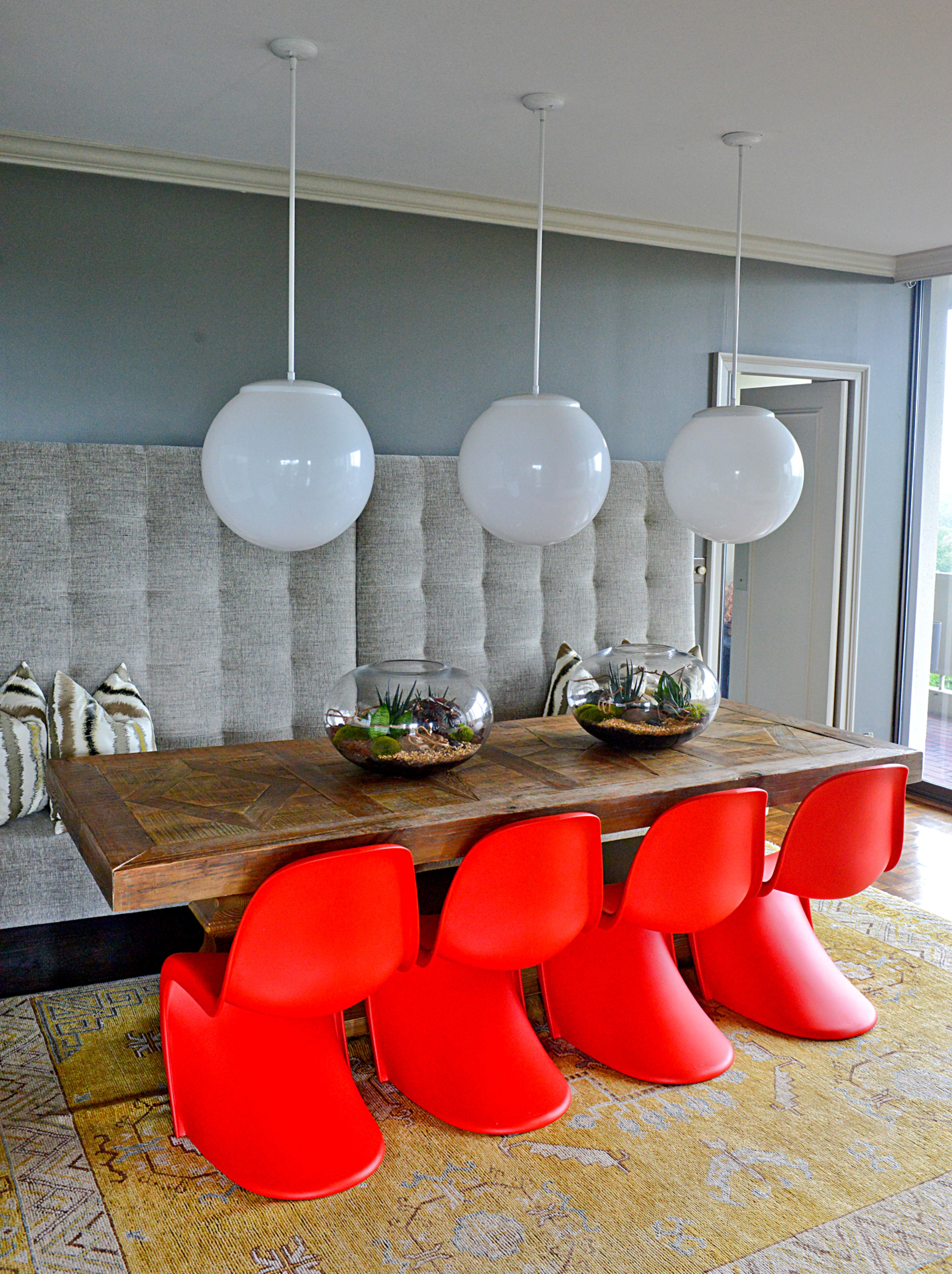 Jason Moattar wanted to add playfulness and personality to his condo's dining space. To do so, he positioned bright red chairs from Design Within Reach and a recovered banquette in gray fabric around a farm table found at Four Hands.