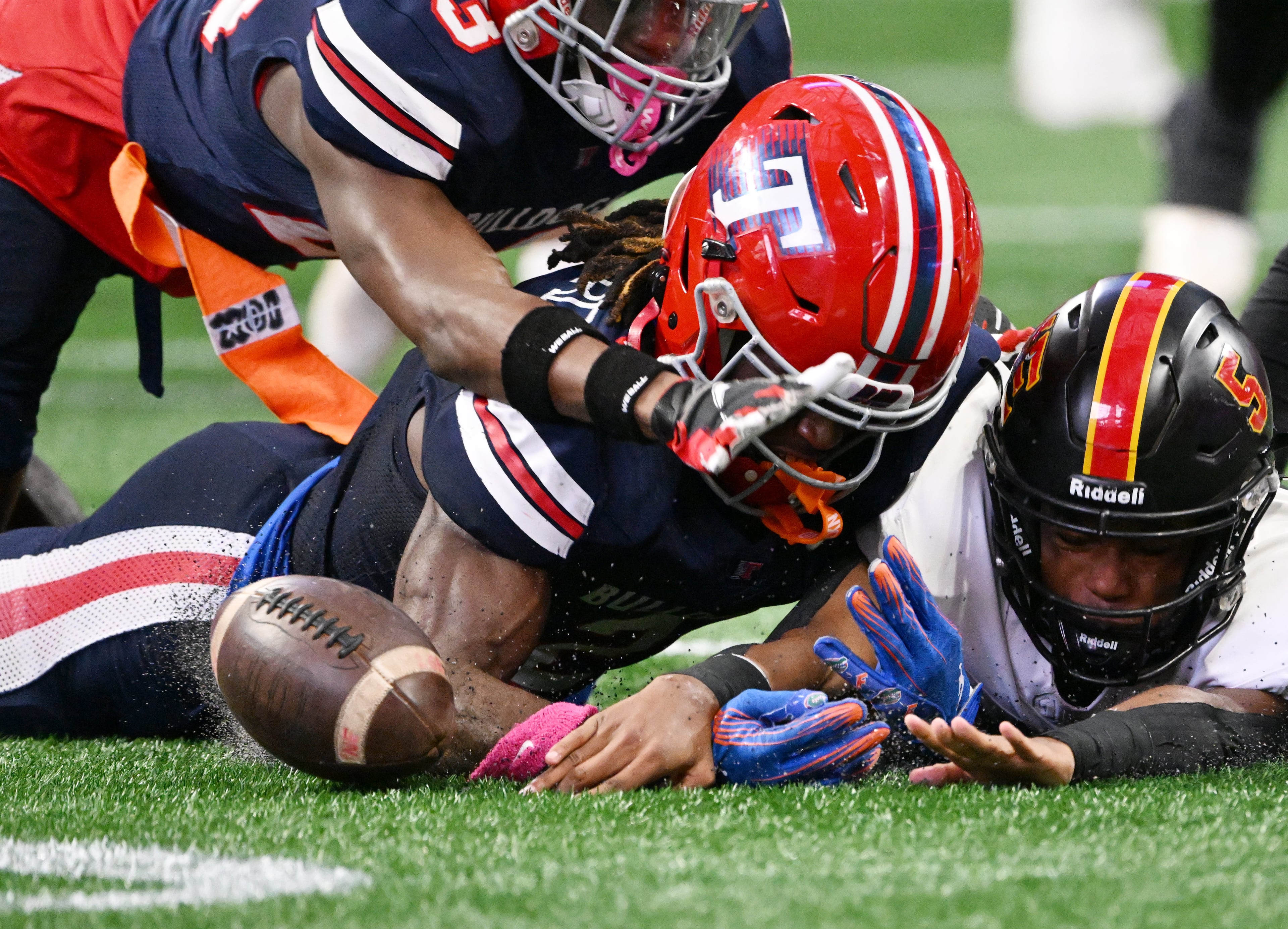 Toombs County's Alex Scott (left) Toombs County's Lagonza Hayward (center) and Northeast's Reginald Glover (5) fight to recover the fumble by Northeast's running back Nick Woodford during the first half in GHSA Class A-Division State Championship game at Mercedes-Benz Stadium, Tuesday, December 17, 2024, in Atlanta. (Hyosub Shin / AJC)