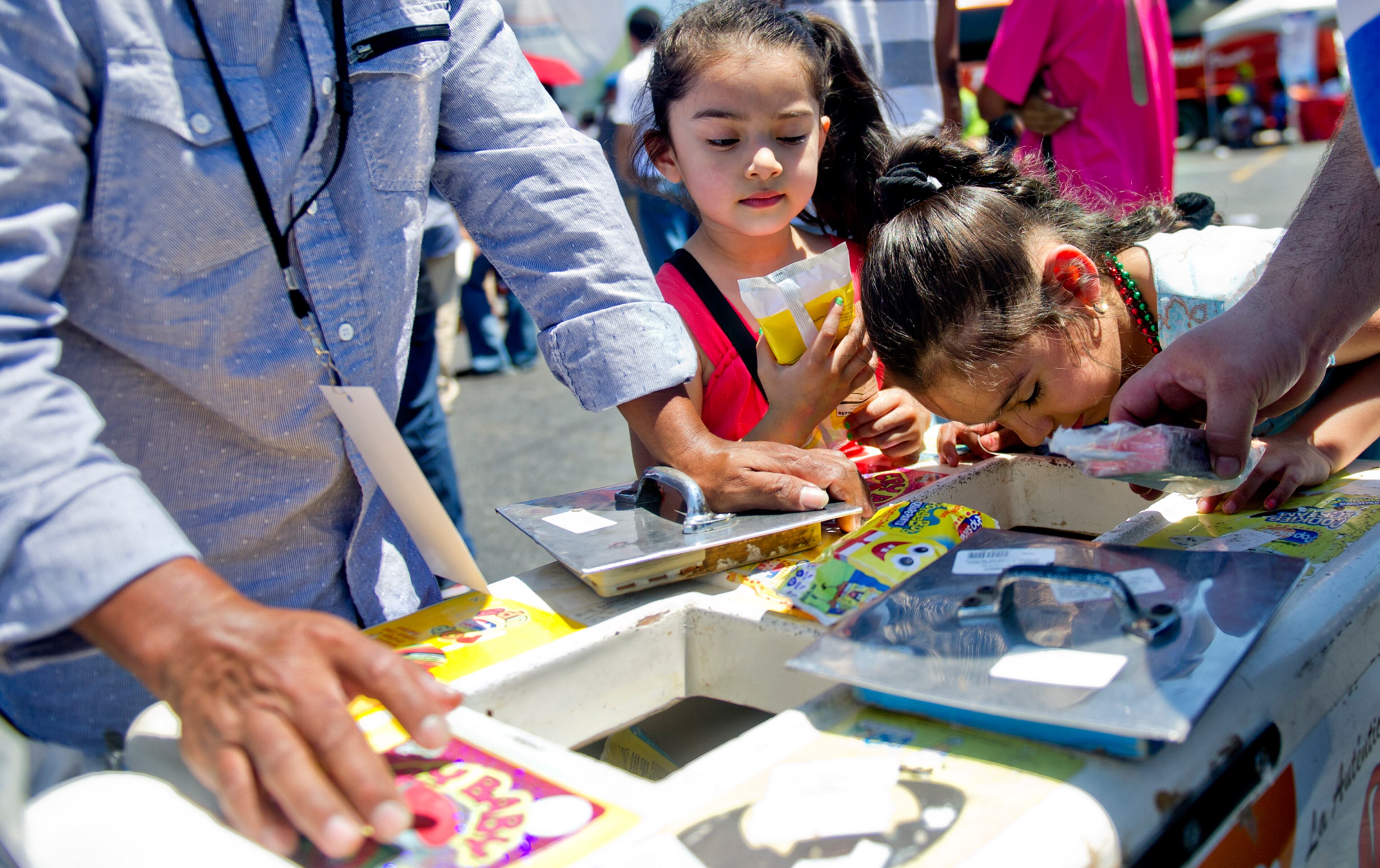 Joselyn Correa (right) and her sister Janice figure out which type of ice cream bar they want during the Cinco de Mayo Festival at Plaza Fiesta in Atlanta on Sunday, May 4, 2014.