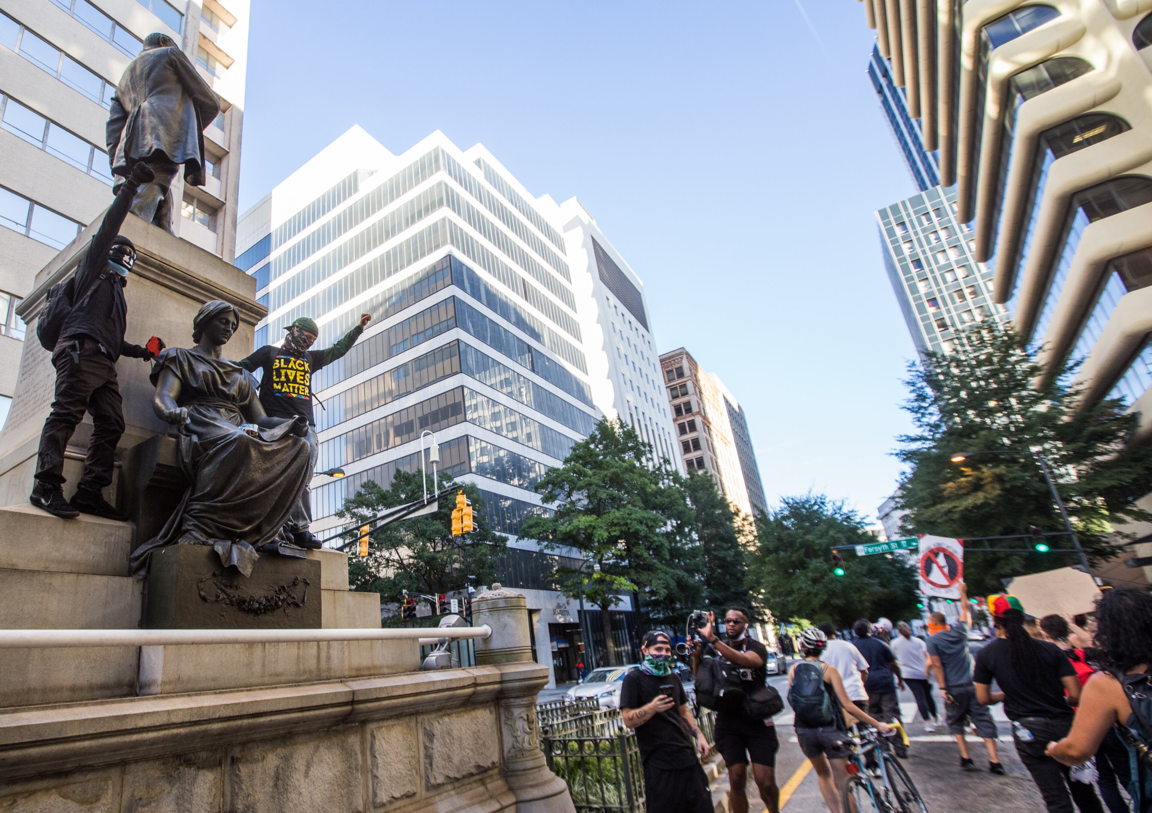 Protesters march down Marietta Street and pose on the Henry W. Grady statue on Saturday, September 5, 2020. The protest started at Ebenezer Baptist Church as a political gathering and joined a Black Lives Matter protest at CNN Center with a heavy police escort along the way. (Jenni Girtman for The Atlanta Journal-Constitution)