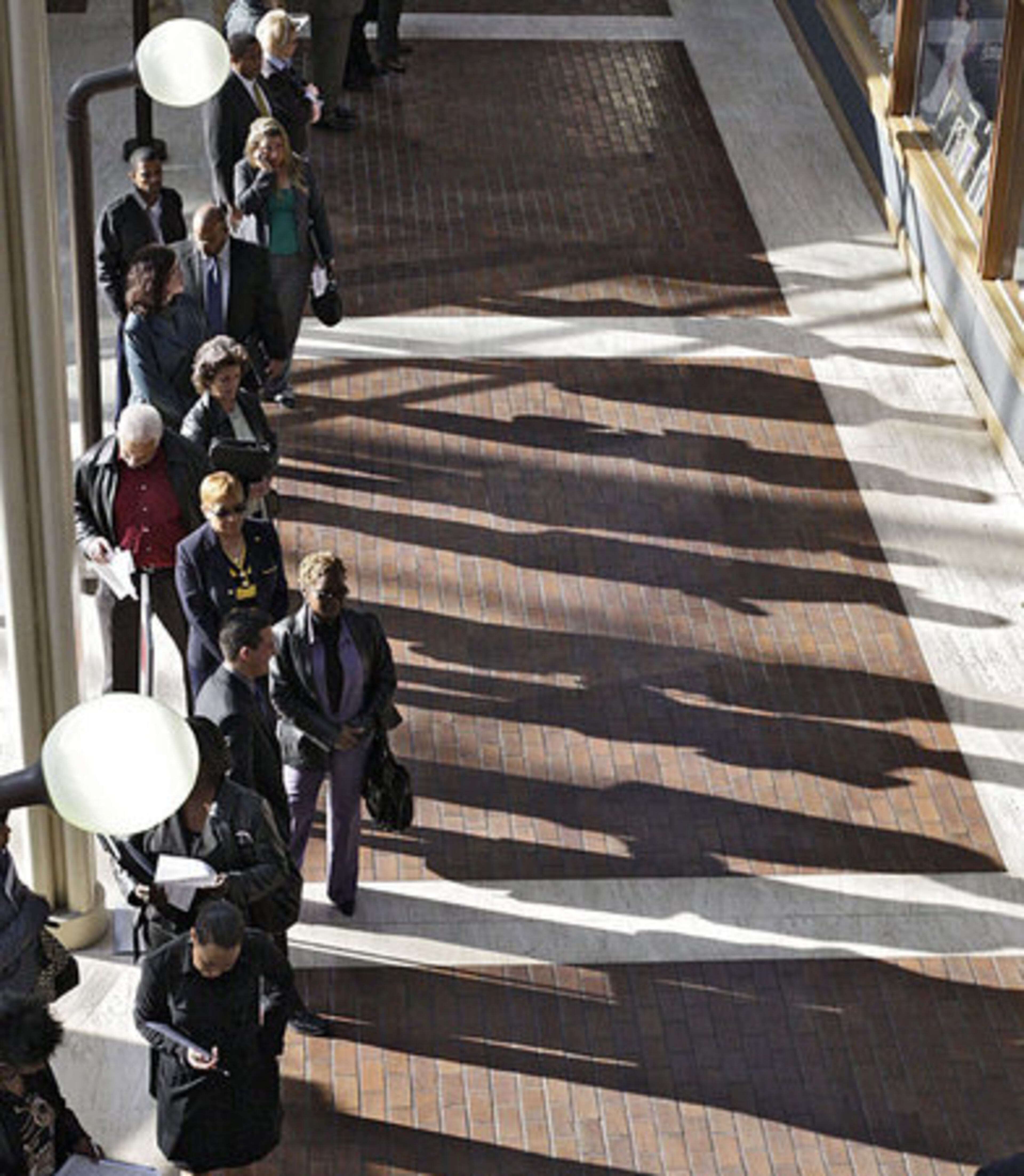 Job seekers cast a long shadow in the morning light as several hundred were in line before the opening of the job fair. Organizers said the fair almost didn't happen until some companies signed up at the last minute.