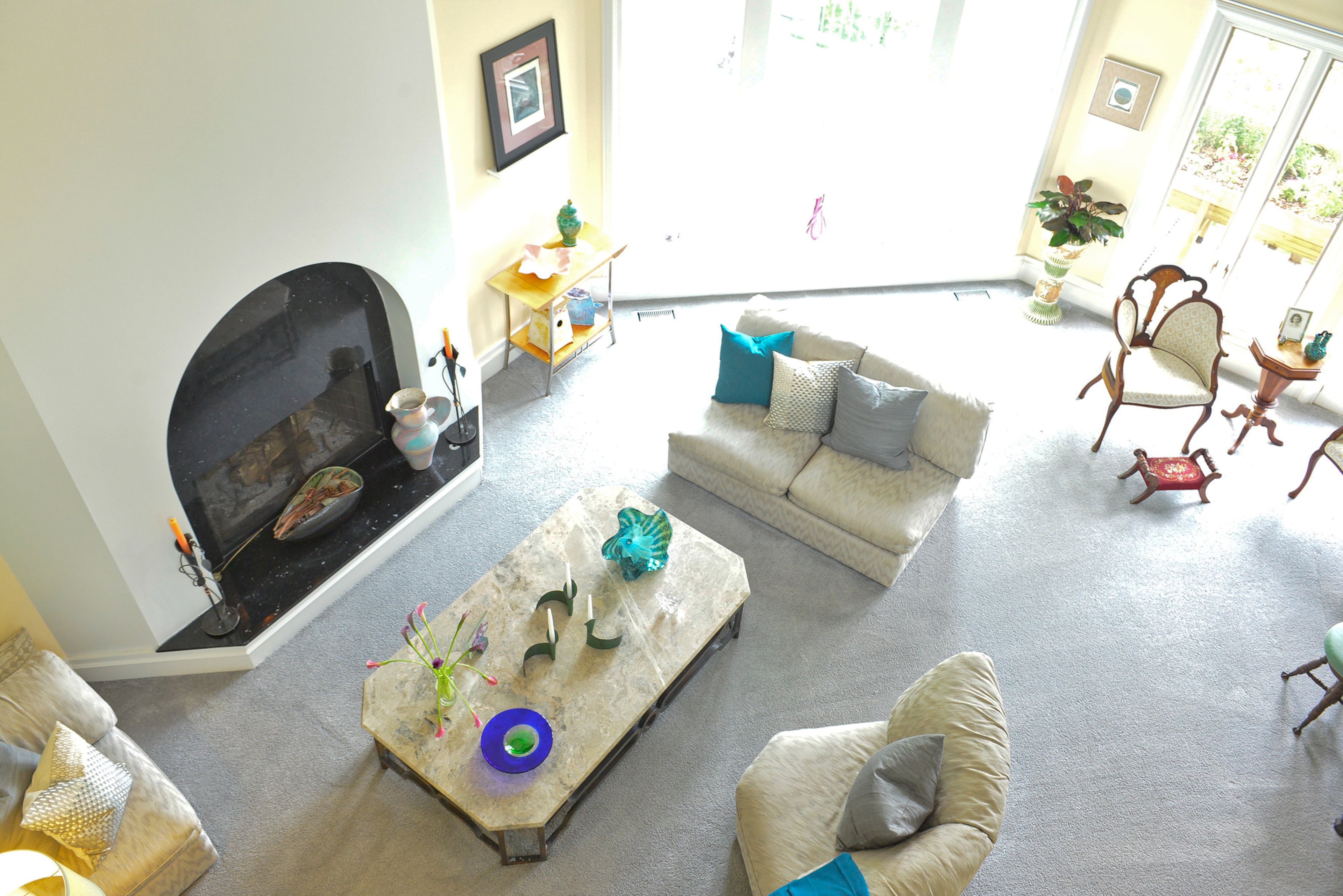A simple yet stunning fireplace featuring a black granite arch centers the living room, seen from the second floor bridge. The carpet is from Moda Floors & Interiors.