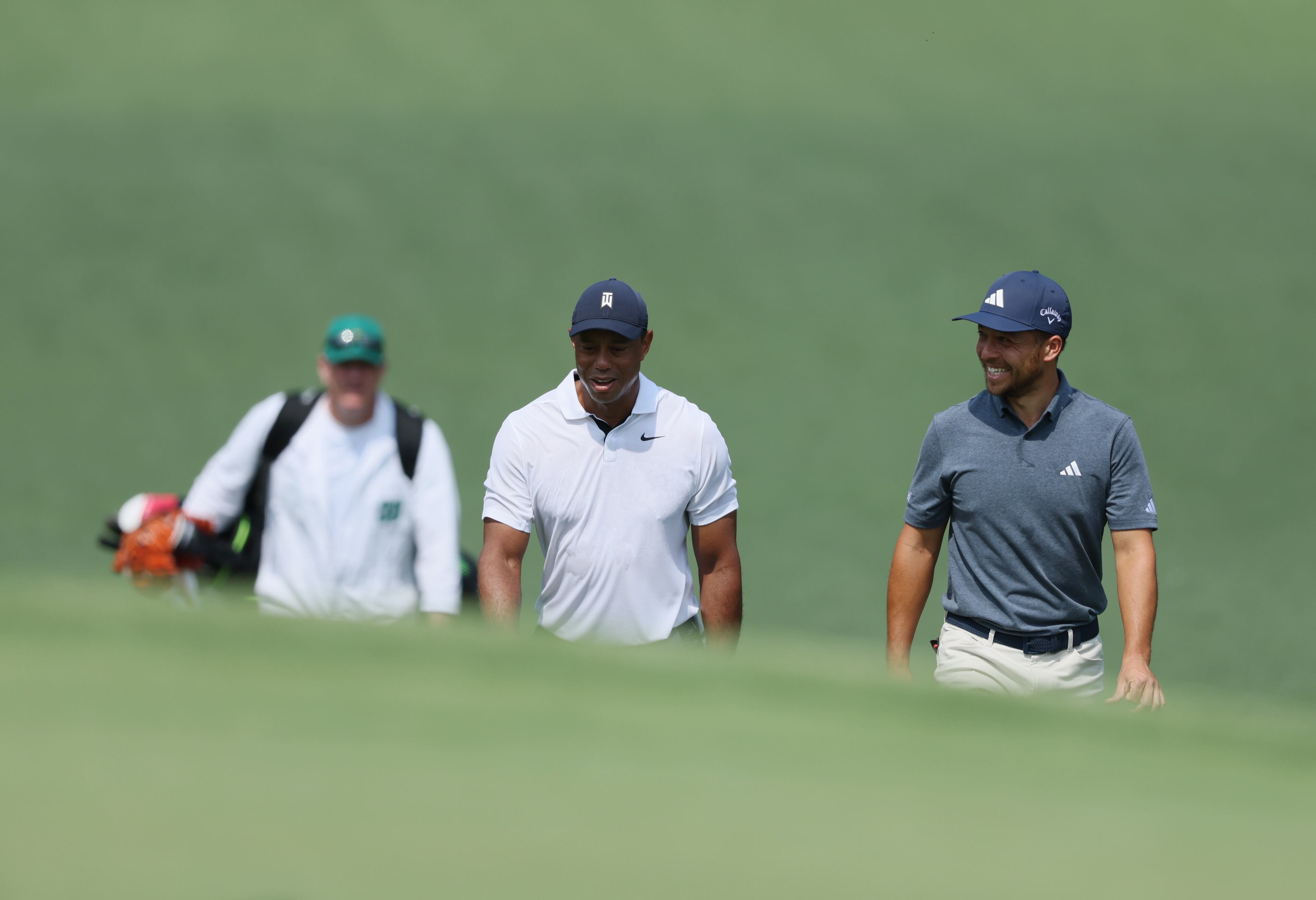 Tiger Woods and Xander Schauffele walk down fairway on seventh hole on the first round of the 2023 Masters Tournament at Augusta National Golf Club, Thursday, April 6, 2023, in Augusta, Ga. (Jason Getz / Jason.Getz@ajc.com)