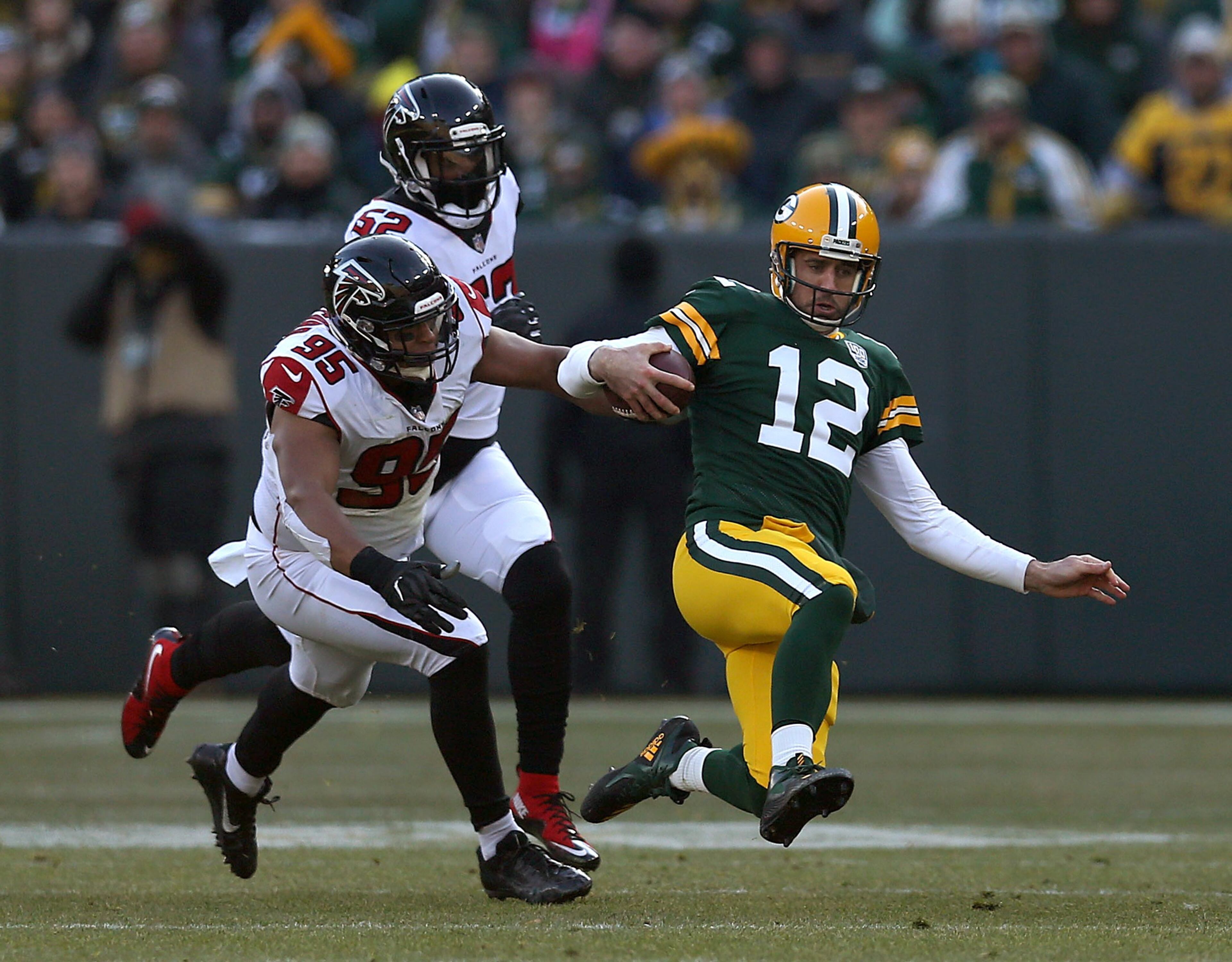 GREEN BAY, WISCONSIN - DECEMBER 09: Aaron Rodgers #12 of the Green Bay Packers slides in front of Jack Crawford #95 of the Atlanta Falcons and Bruce Irvin #52 during the first half of a game at Lambeau Field on December 09, 2018 in Green Bay, Wisconsin. (Photo by Dylan Buell/Getty Images)