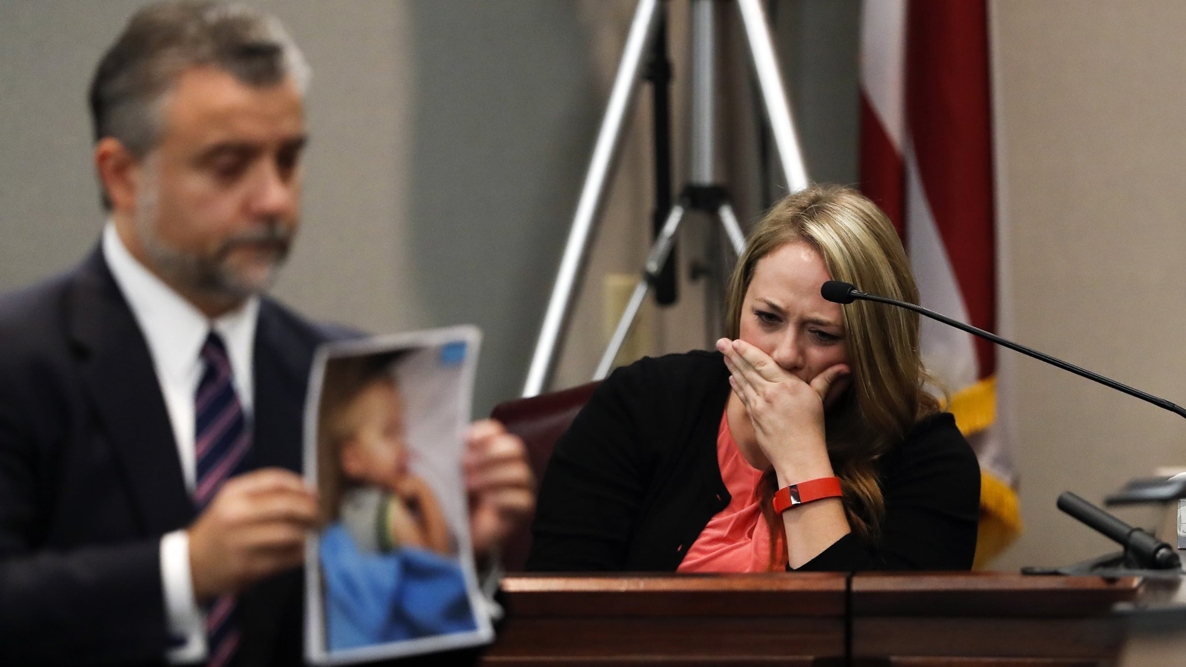 As defense attorney Maddox Kilgore holds up a photo of Cooper Harris for the jury on Monday, Leanna Taylor weeps on the witness stand in the background. (AP Photo/John Bazemore, Pool)