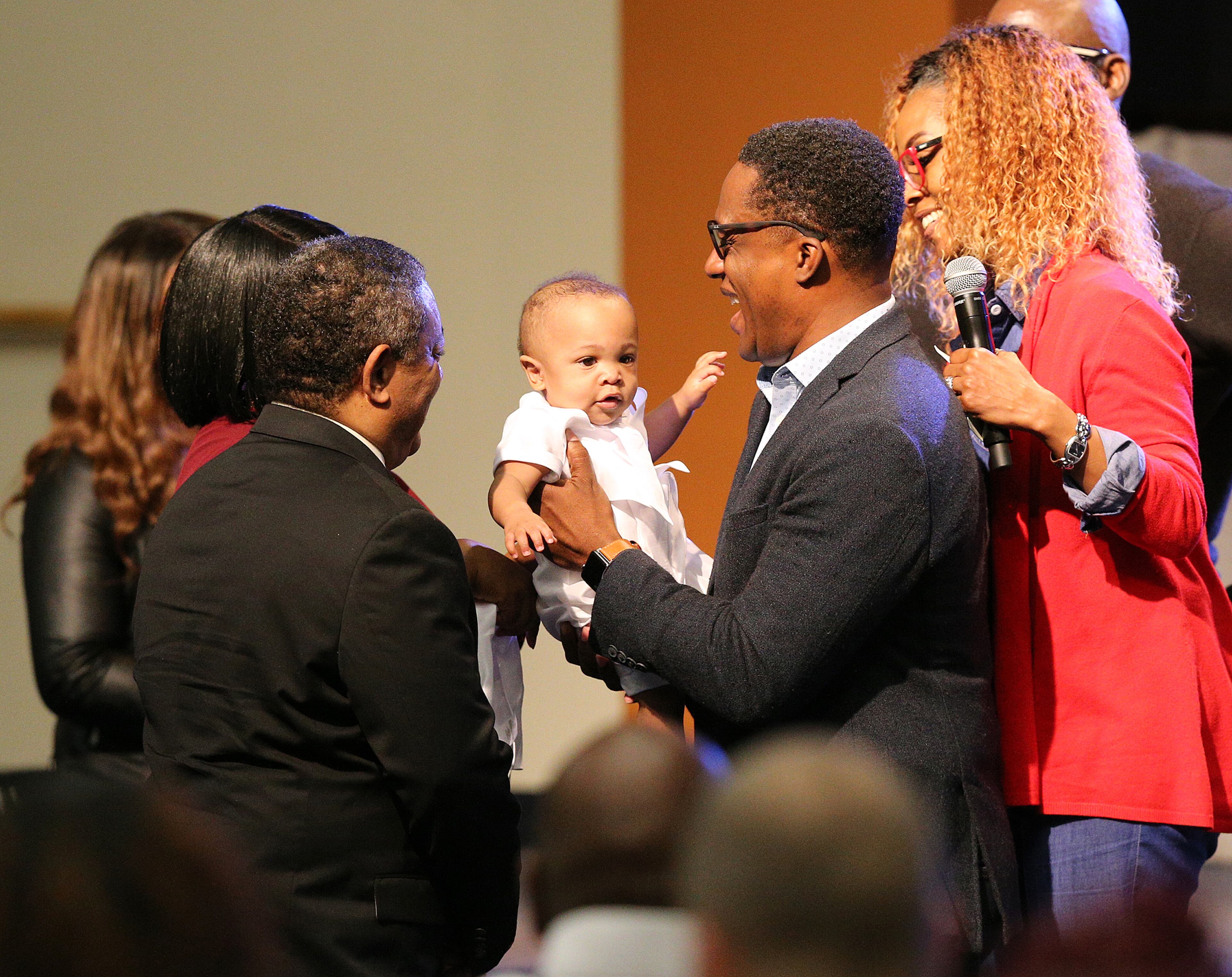 March 15, 2020 Austell: Pastor Wilbur Purvis III (right) dedicates infant Michael Kirkland to the Lord while preaching on the coronavirus saying âdonât let coronavirus steal your praiseâ during worship service at Destiny World Church on Sunday, March 15, 2020, in Austell. The congregation took a special offering to adopt a local apartment complex to supply lunch to needy school children the next two weeks. Curtis Compton ccompton@ajc.com