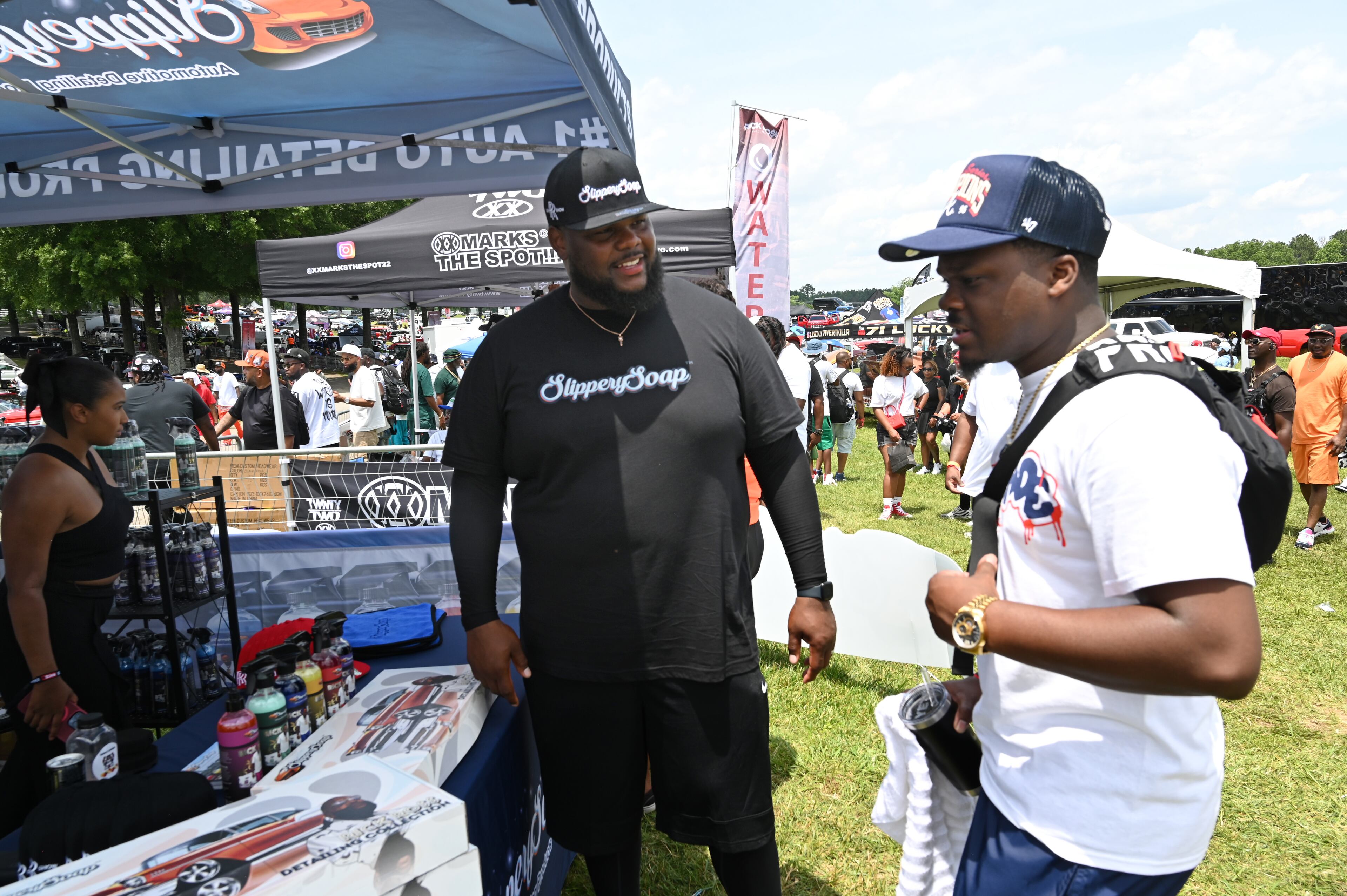 Jeremy Lewis (left), founder of Slippery Soap, talks to an attendee during the 4th Annual Rick Ross Car and Bike Show, Saturday, June 7, 2025, in Fayetteville. The 4th Annual Rick Ross Car and Bike Show will include a vendor market with more than 30 vendors, food trucks, fleets of classic/custom automobiles, luxury vehicles, boats, RVs and trailers on the front of the mansion. Stage performances include Plies, Ross' new signee Nino Breeze and Ross himself. (Hyosub Shin / AJC)