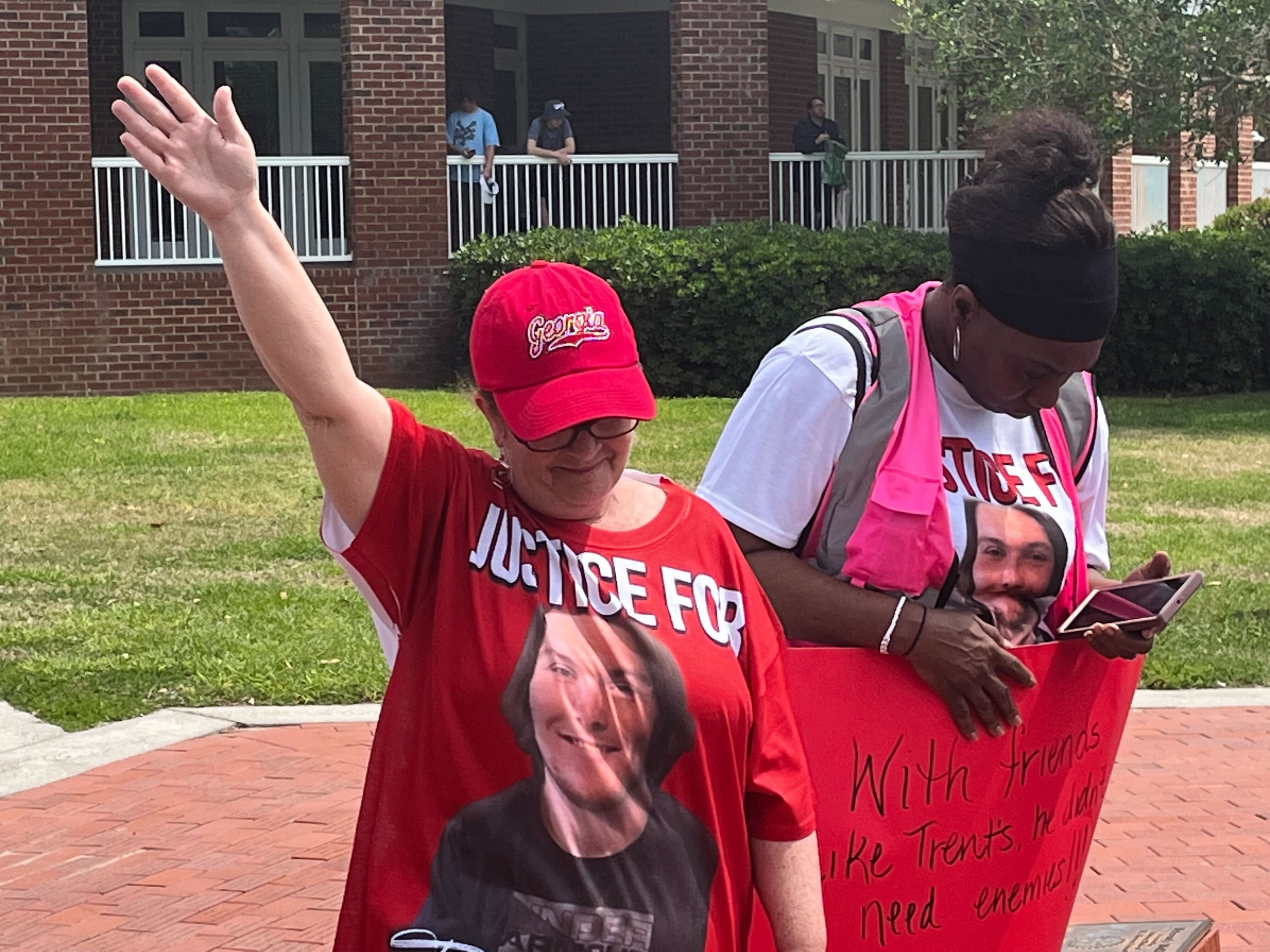 A woman wearing a "Justice for Trent" T-shirt holds up her hand during a prayer at the rally.