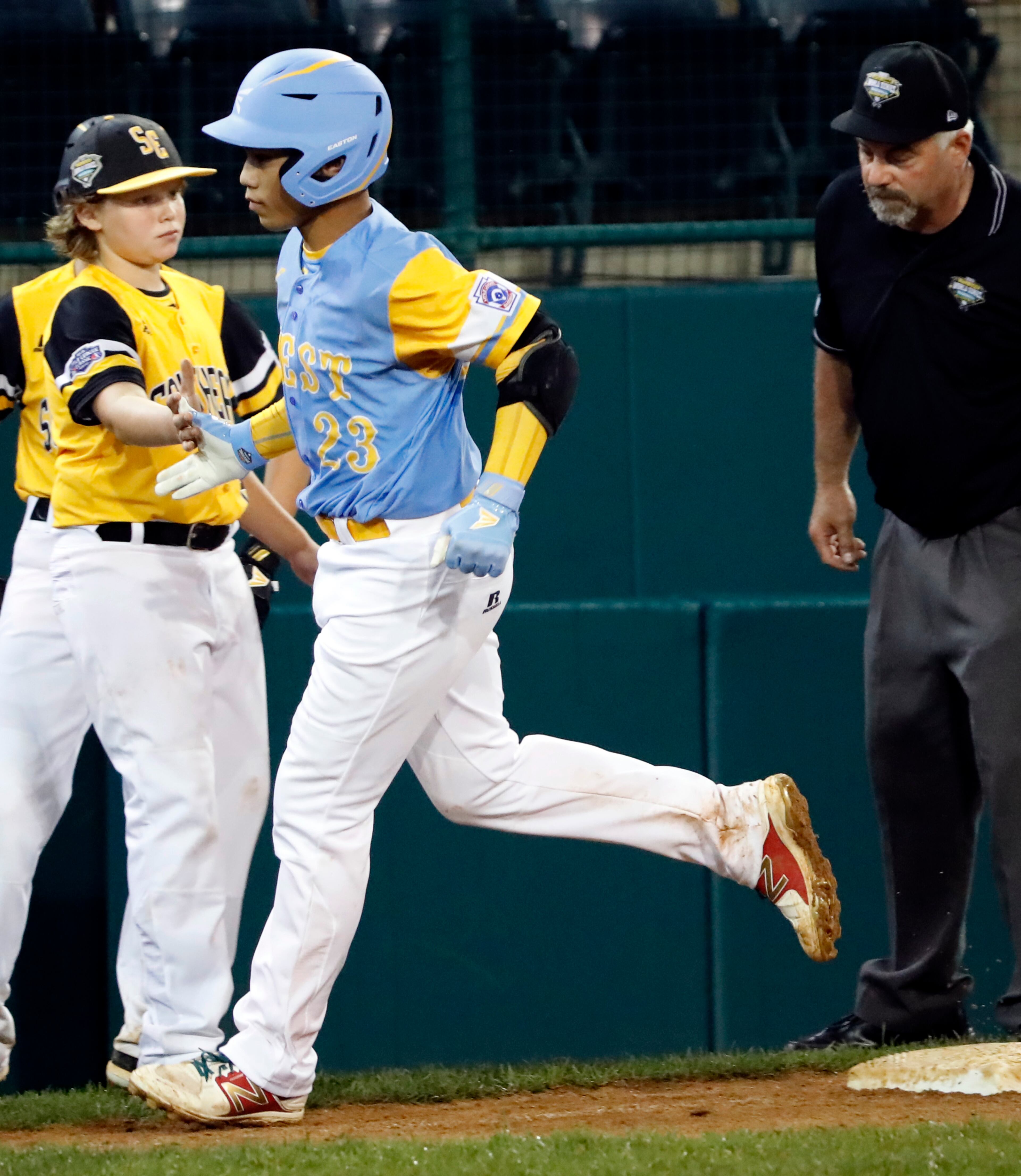 Peachtree City, Ga.'s Jack Ryan reaches out to slap hands with Honolulu's Aukai Kea (23), who rounds third base on his 11th-inning, two-run home run in a baseball game a the Little League World Series in South Williamsport, Pa., Friday, Aug. 17, 2018. (AP Photo/Tom E. Puskar)
